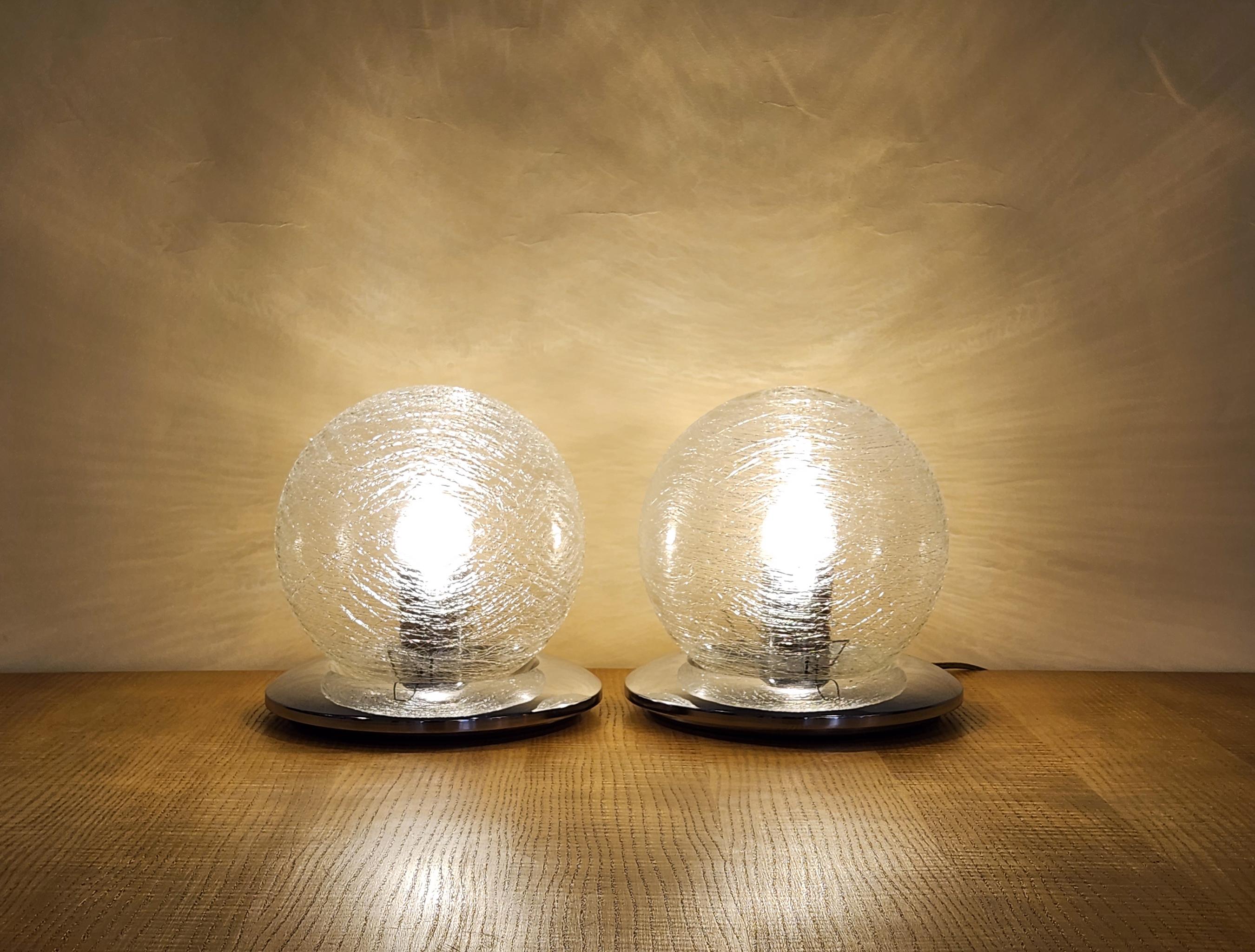A pair of spherical murano glass table lamps, originating from Italy circa 1970. Each lamp consists of a glass orb sat on top of a metal base. The glass has been handblown, and features a fibrous textured effect. Stylish, mysterious, and an