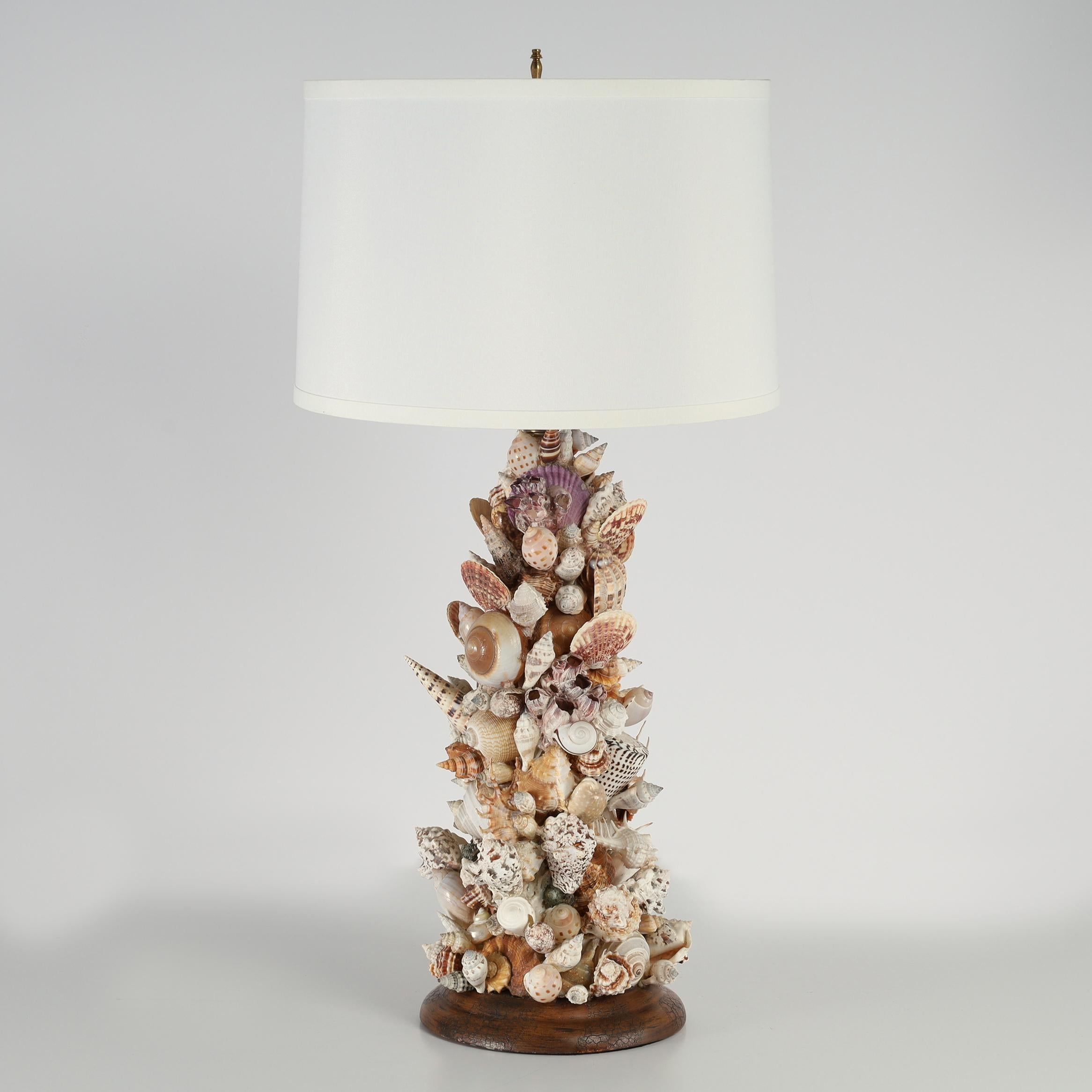 Standout pair of large table lamps ambitiously handcrafted in a grotto style assemblage of exotic seashells and presented on tuned wood bases. 