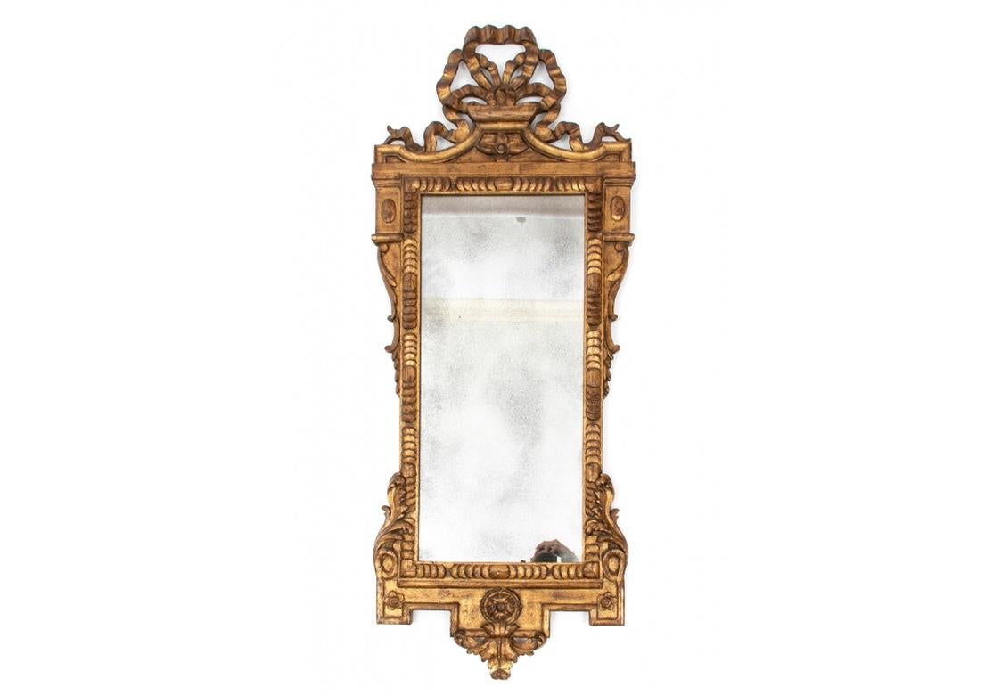 Fine pair of vintage Gilt Wood mirrors feature well-carved bow crests and extensive work to the border with well shaped frames. The gilt wood frames house rectangular mirrors that display well. 
Each Mirror measures 53