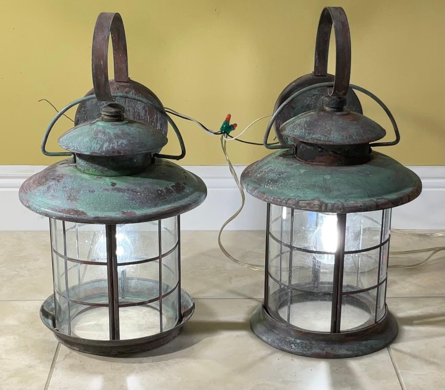 Elegant pair of wall lantern handcrafted of solid brass, quality workmanship, electrified with one 100/watt light each, decorative brass trimming around the glass. Great light exposure.
Suitable for wet location. 
The lantern are slightly different