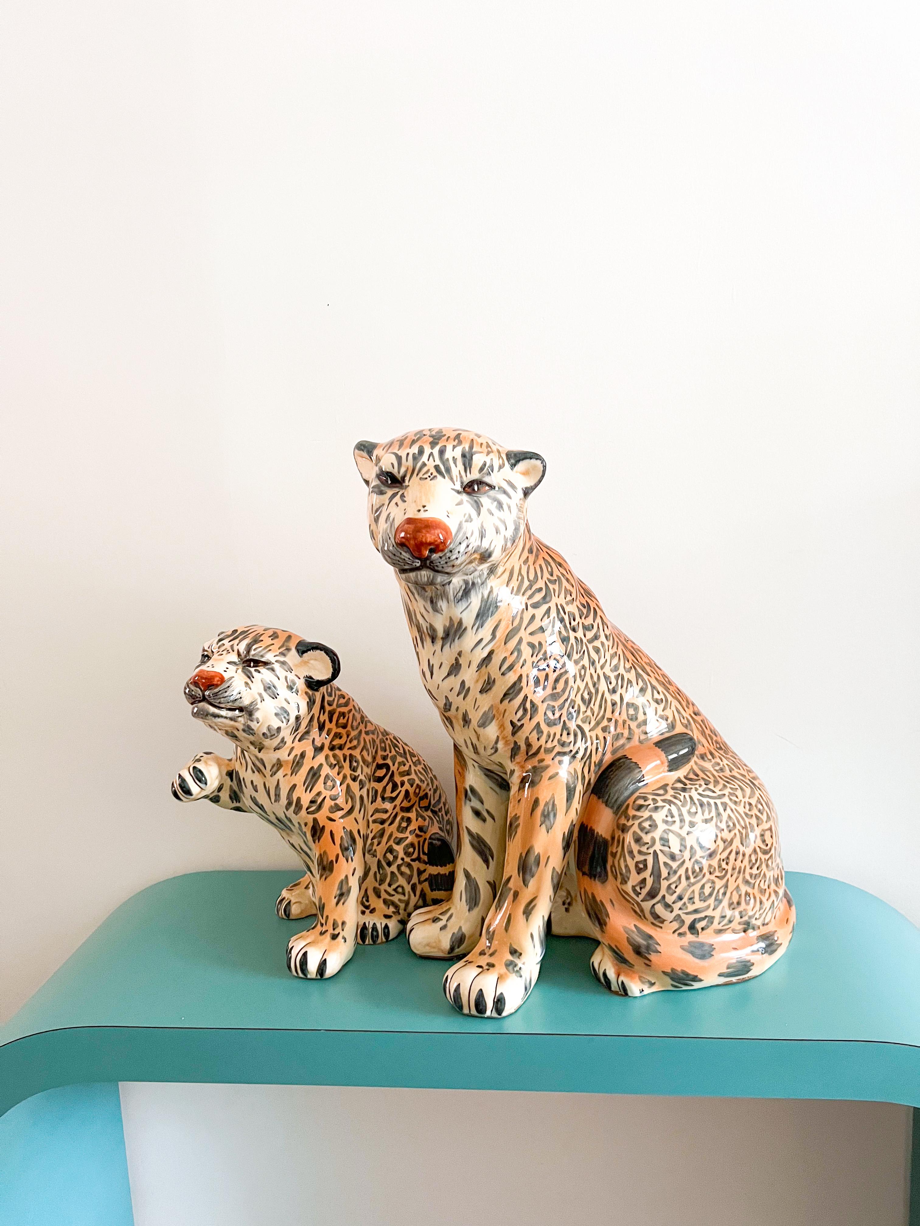Pair of vintage ceramic leopards, portraying a mother and cub with striking realism. These sculptures showcase meticulous craftsmanship, featuring glazed ceramic finishes that capture the essence of fur and intricate facial expressions. Notably,
