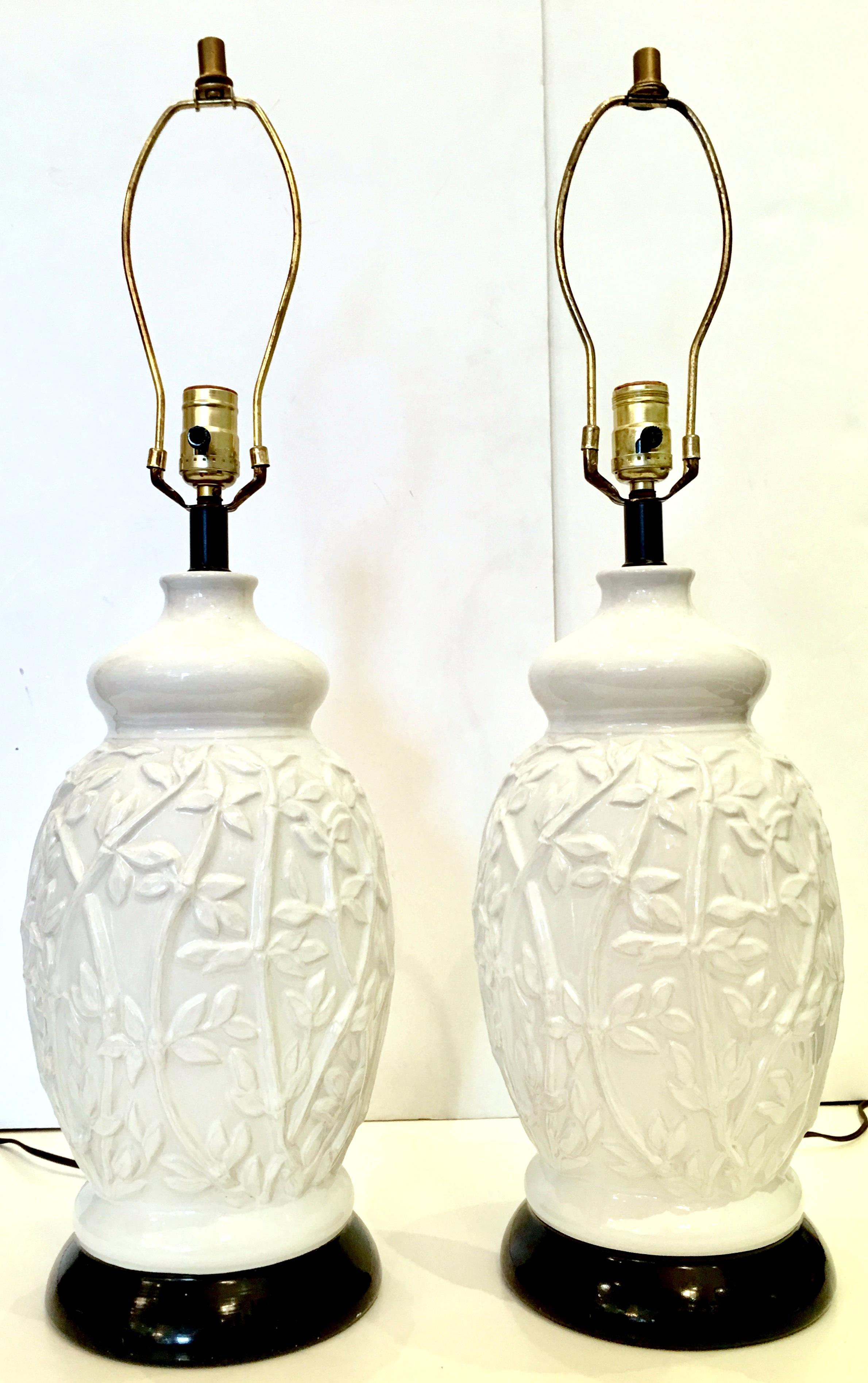 1960'S Hollywood Regency Pair of bright white large ceramic glaze ginger jar style high relief faux bamboo table lamps. Features a bright whit high relief faux bamboo motif with black ceramic base and original brass fittings. Includes a pair of