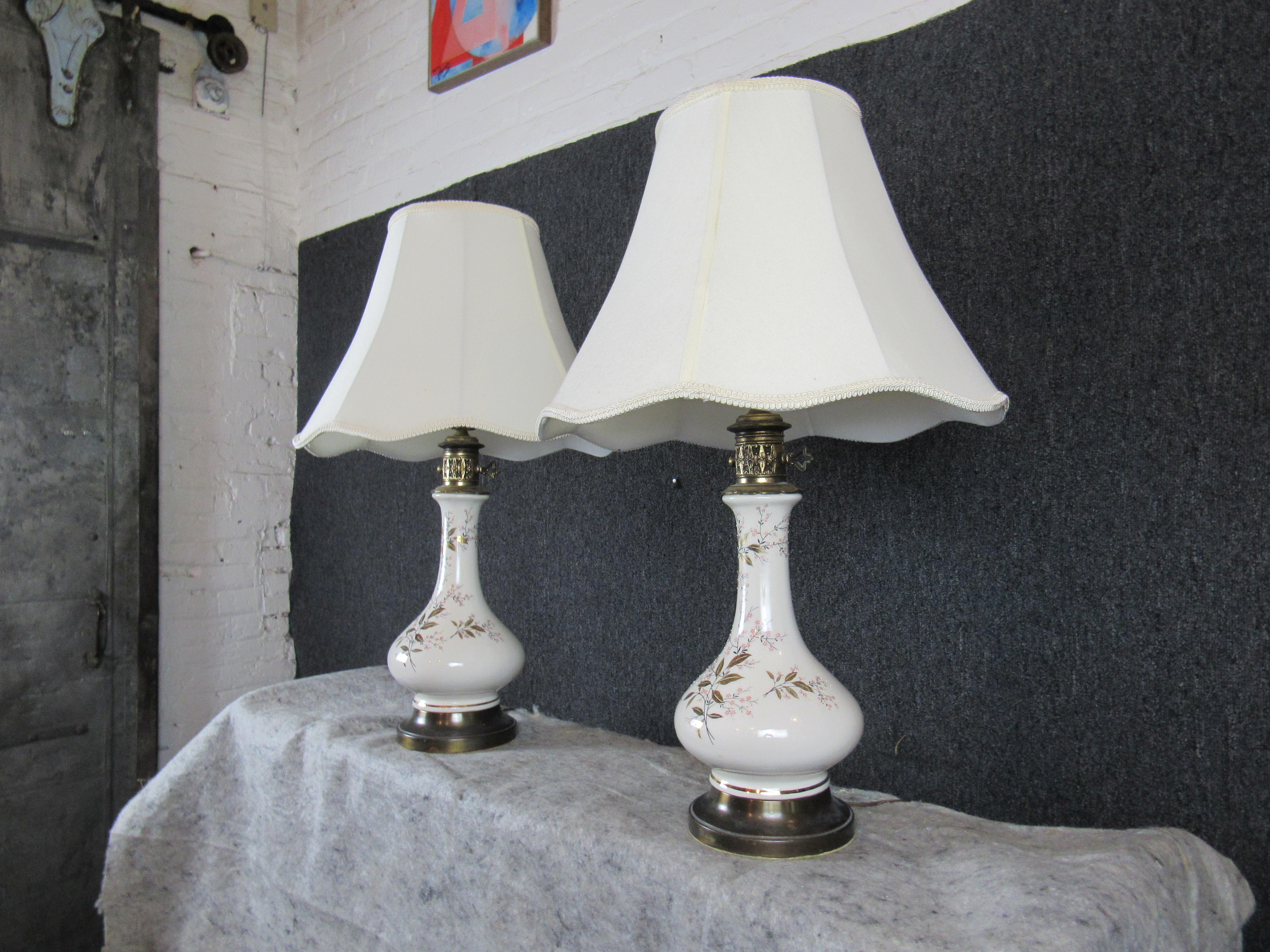 Hübsches Paar Vintage-Genie-Lampen mit unendlichem Charme! Eine hübsche Keramikvase ist mit einem gemalten Kirschblütenmotiv verziert, während Messingakzente einen Hauch von altmodischer Eleganz verleihen. Die bauschigen Stoffschirme verleihen jedem
