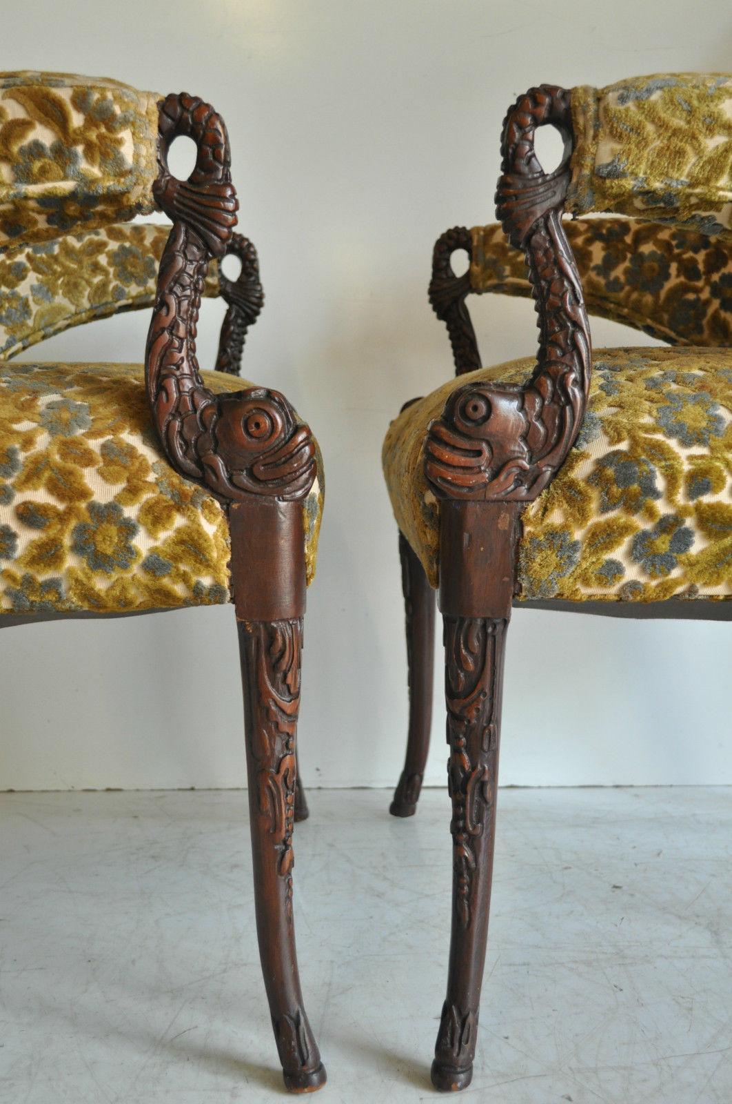 Pair of incredible vintage Hollywood Regency carved mahogany dolphin fireside armchairs. The chairs feature a great shape with floating tapered arms that terminate in nicely carved stylized dolphins, which connect the arms to classically carved