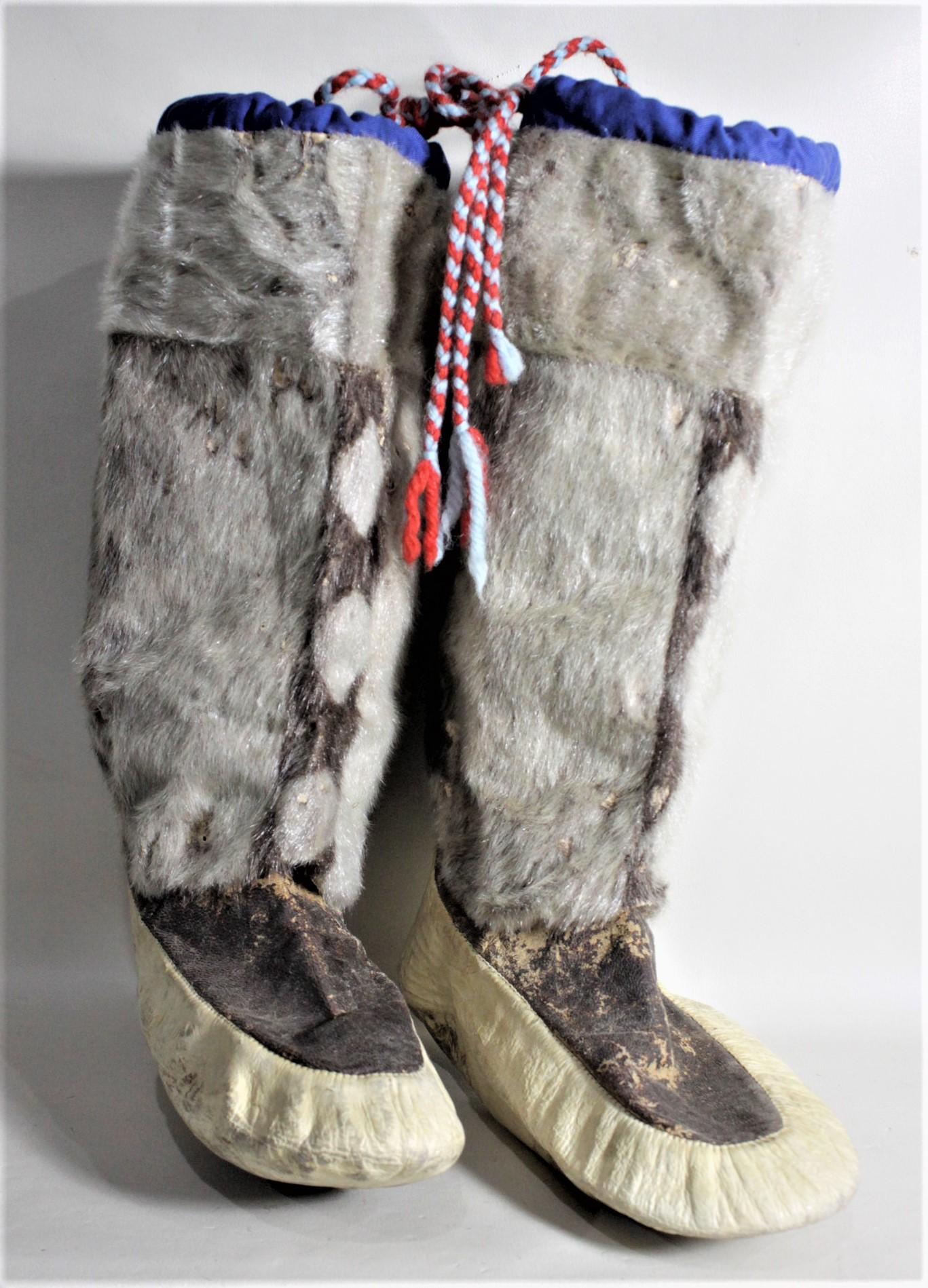 This pair of vintage Inuit mukluks are presumed to have been made in Canada in circa 1950 in the Indigenous American Folk Art style. The upper portions are made with fur and the bottom or 'boot' is composed of leather. There are wool ties done in