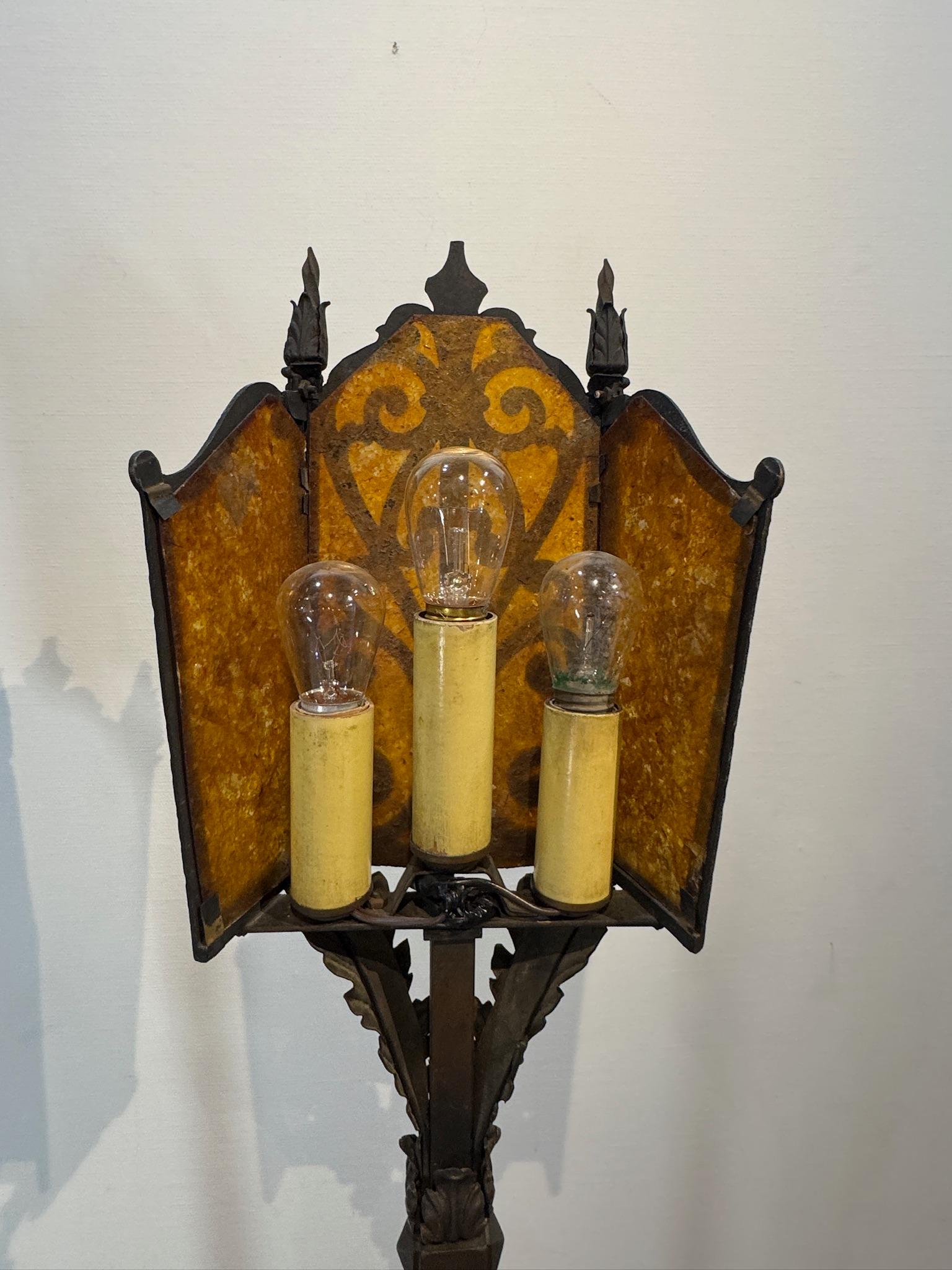 Elevate your space with this stunning pair of vintage wrought iron floor lamps, featuring intricately designed bases and gorgeous amber mica lantern shades. Crafted in a Mission or Arts & Crafts style, these lamps exude old-world charm while