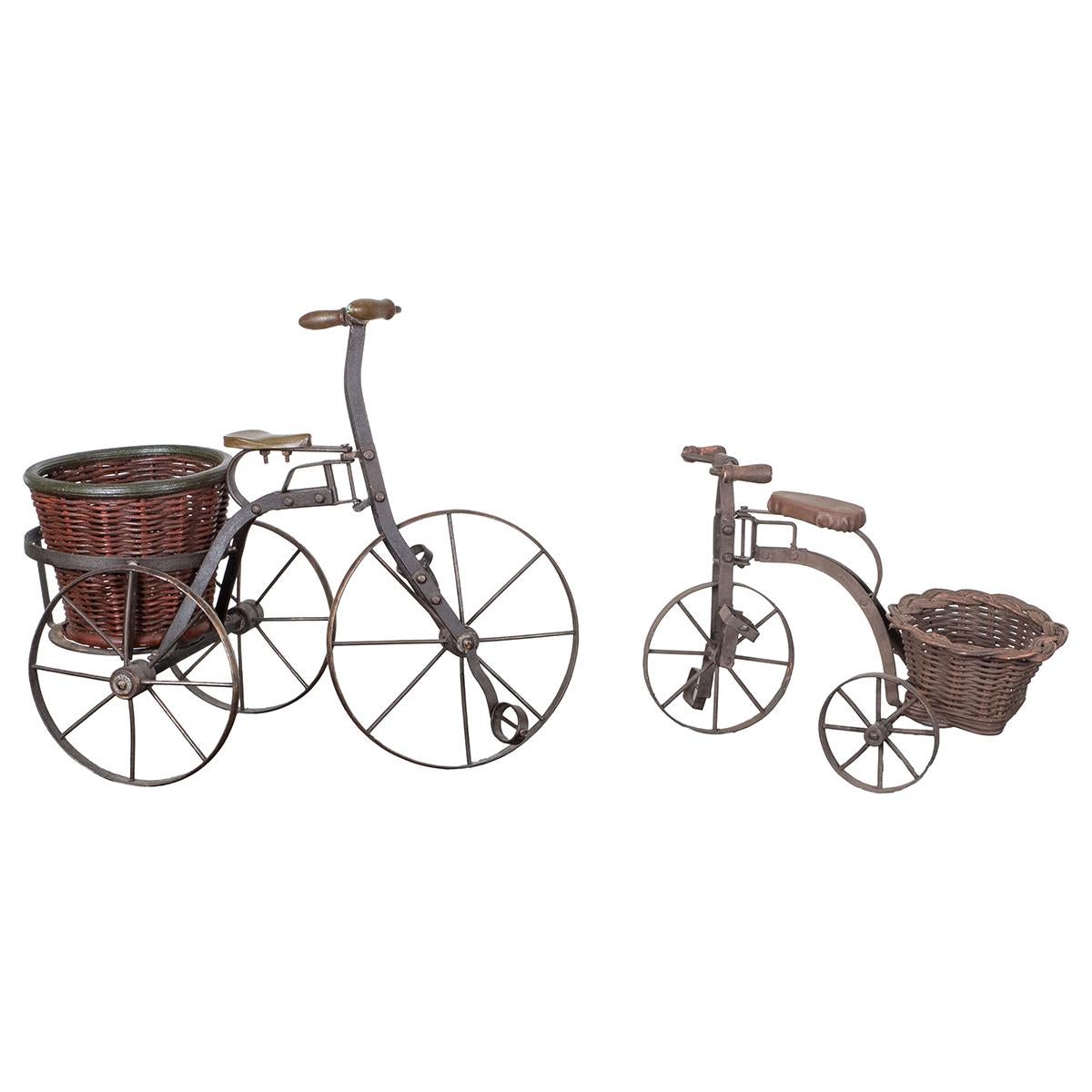 Pair of charming vintage hand-wrought iron tricycle sculptures with wicker cargo baskets.

Large tricycle: 18.5