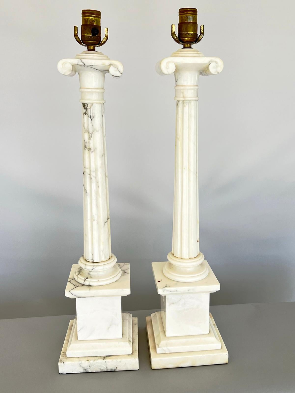 Pair of table lamps, of carved alabaster, each a round, Neoclassical, fluted column, surmounted by an Ionic capital, ending on round foot, and raised on square, graduated plinth base. 

Stock ID: D3613.