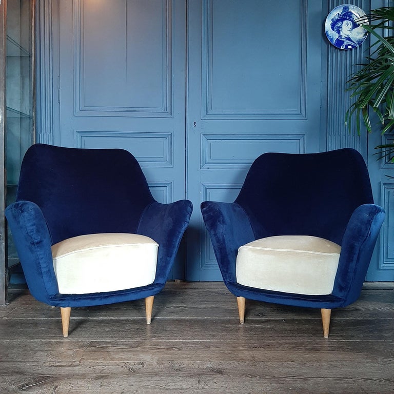 Pair of vintage Italian arm chairs, these Mid-Century Modern chairs from the 1960s are newly upholstered in a rich cobalt blue and crème velvet, and have elegant wooden legs.

Dimensions: H 86 x W 84 x D 73 cm
Seat height 40 cm.
 