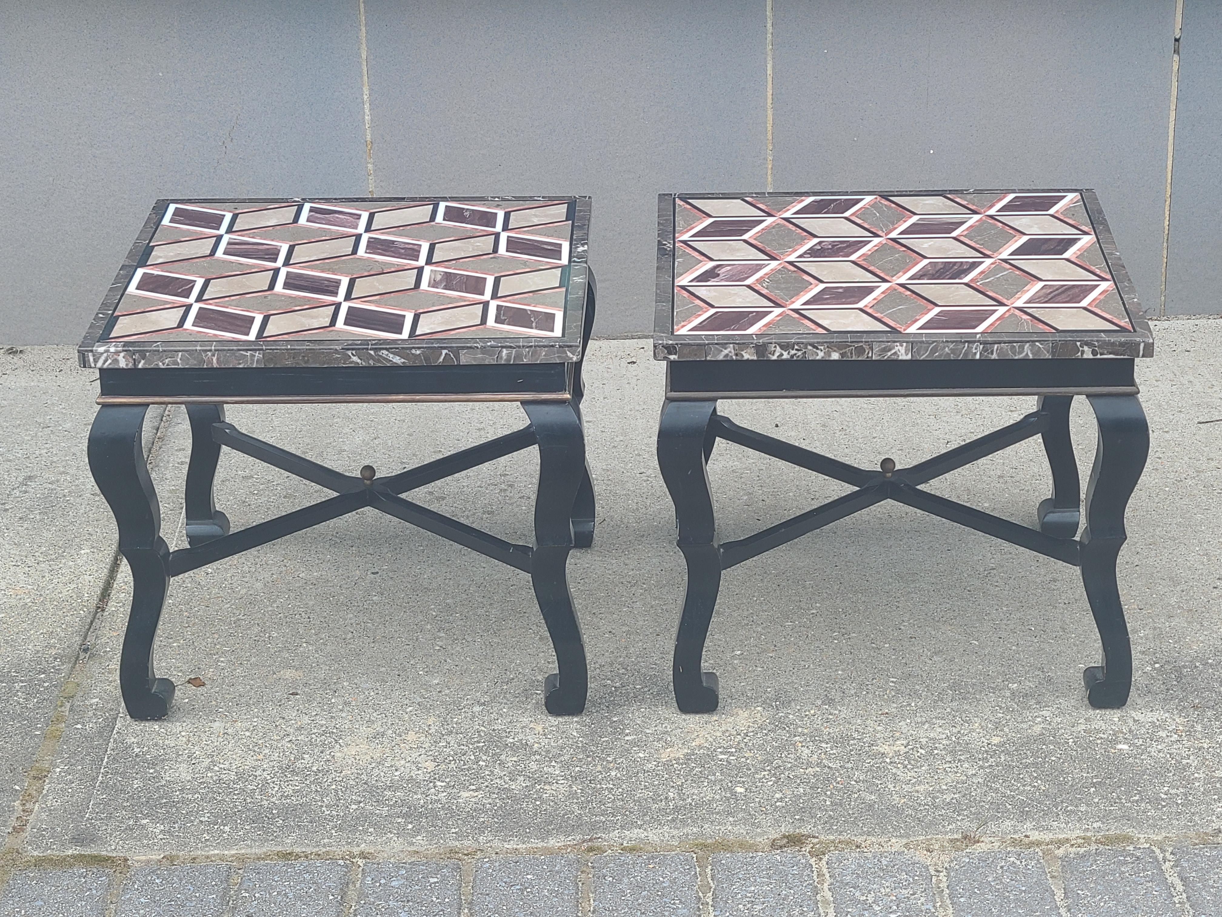 Pair of black lacquered Italian tables with optical inlaid pietra dura marble tops. Pietra dura is inlaid stone that has been ground and polished to a high shine. Tables has aged brass inset in the black lacquer and aged brass finials on the bottom