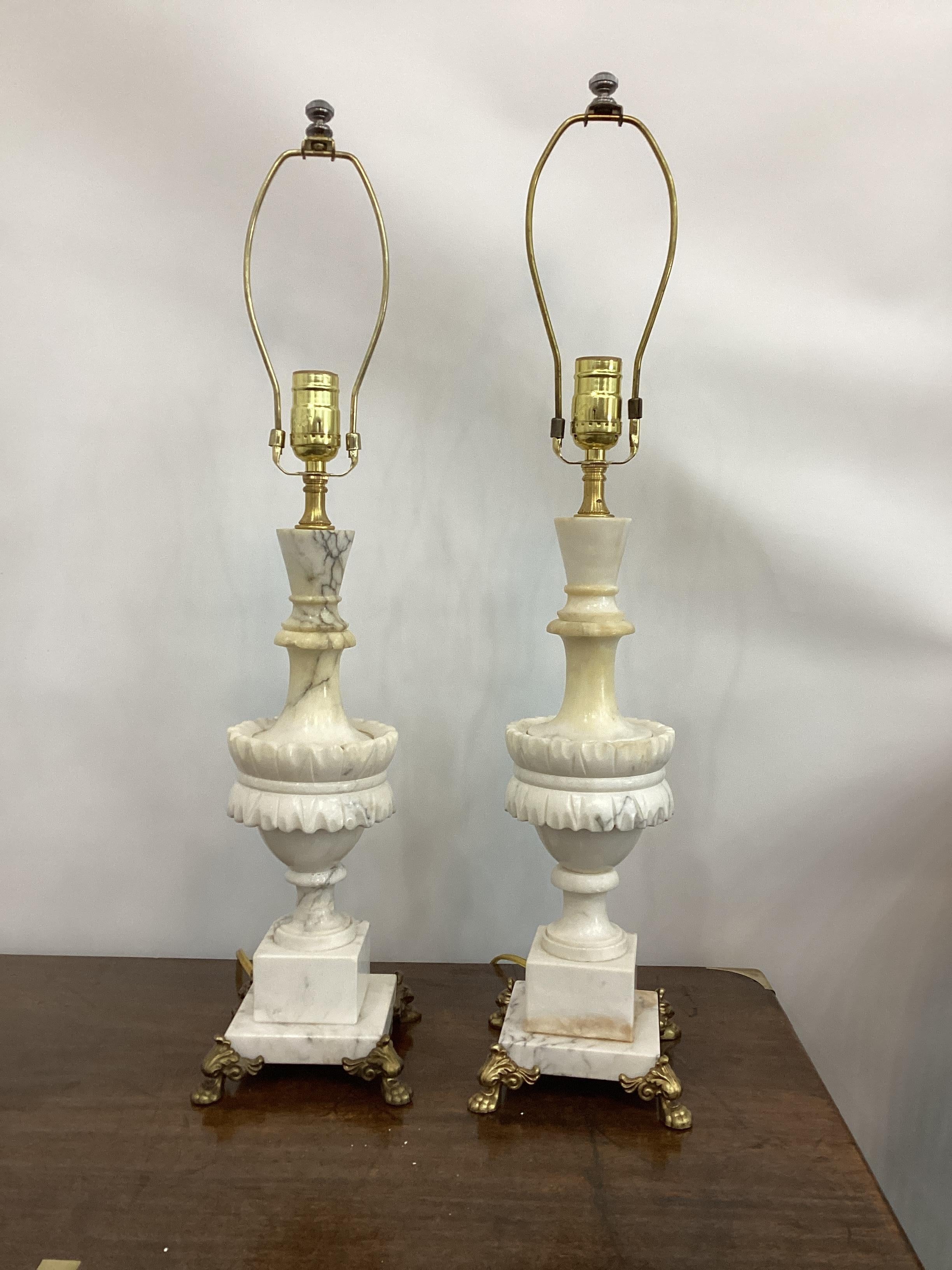 Pair of Vintage Italian Carved Alabaster Lamps. Each raised on a square plinth base sitting on a brass claw footed base. Lamps measure 17” to bottom of the harp. They have been rewired and new sockets.