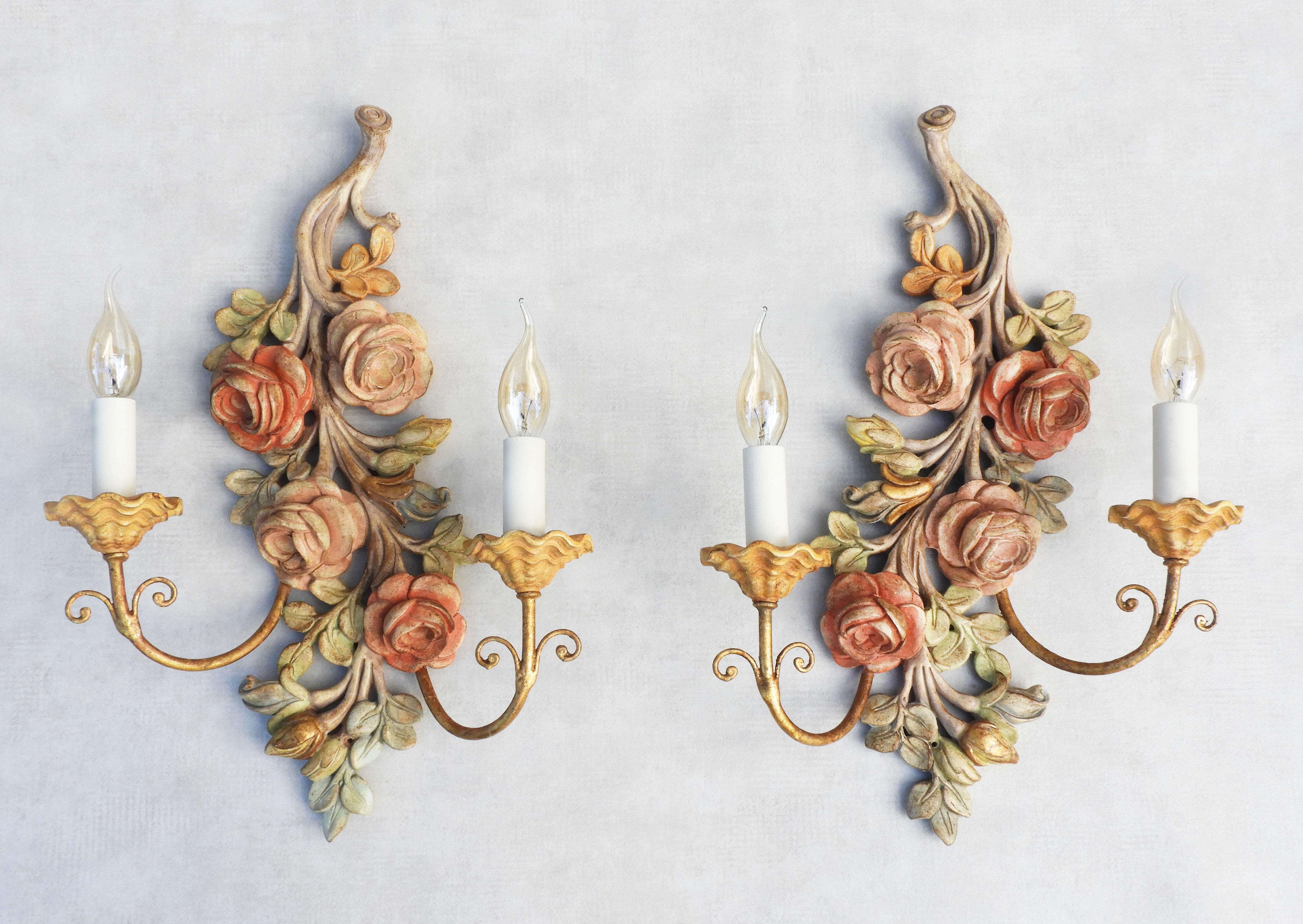 A charming pair of vintage Italian rose flower wall light sconces. Large twin-armed applique lighting beautifully carved and painted, in a subtle polychrome palette, each with two gilt stem 'faux' candlelights.   In great vintage condition with good