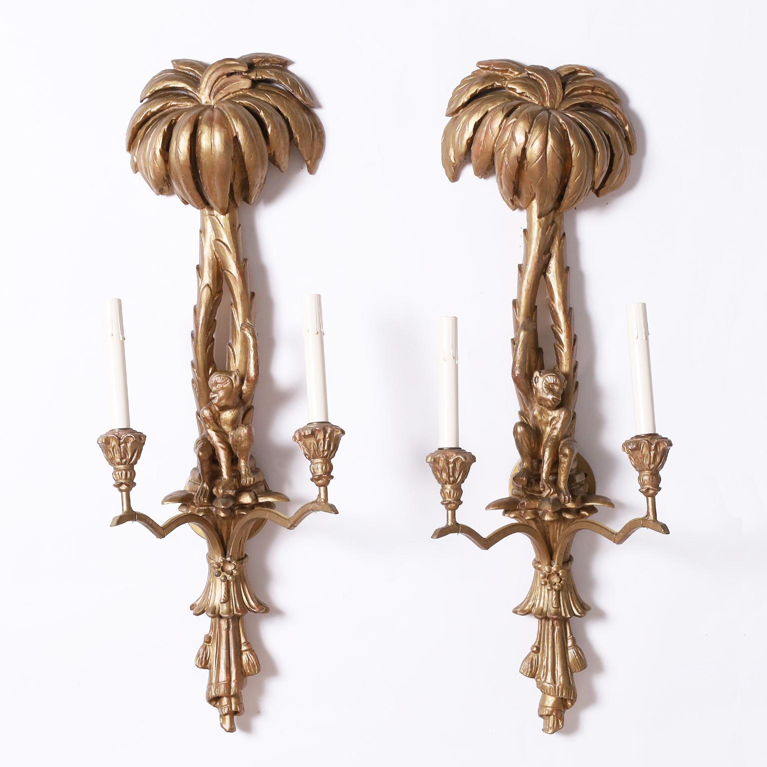Whimsical pair of Italian two light wall sconces crafted in carved wood with palm trees over monkeys and drape and tassels at the bottoms.