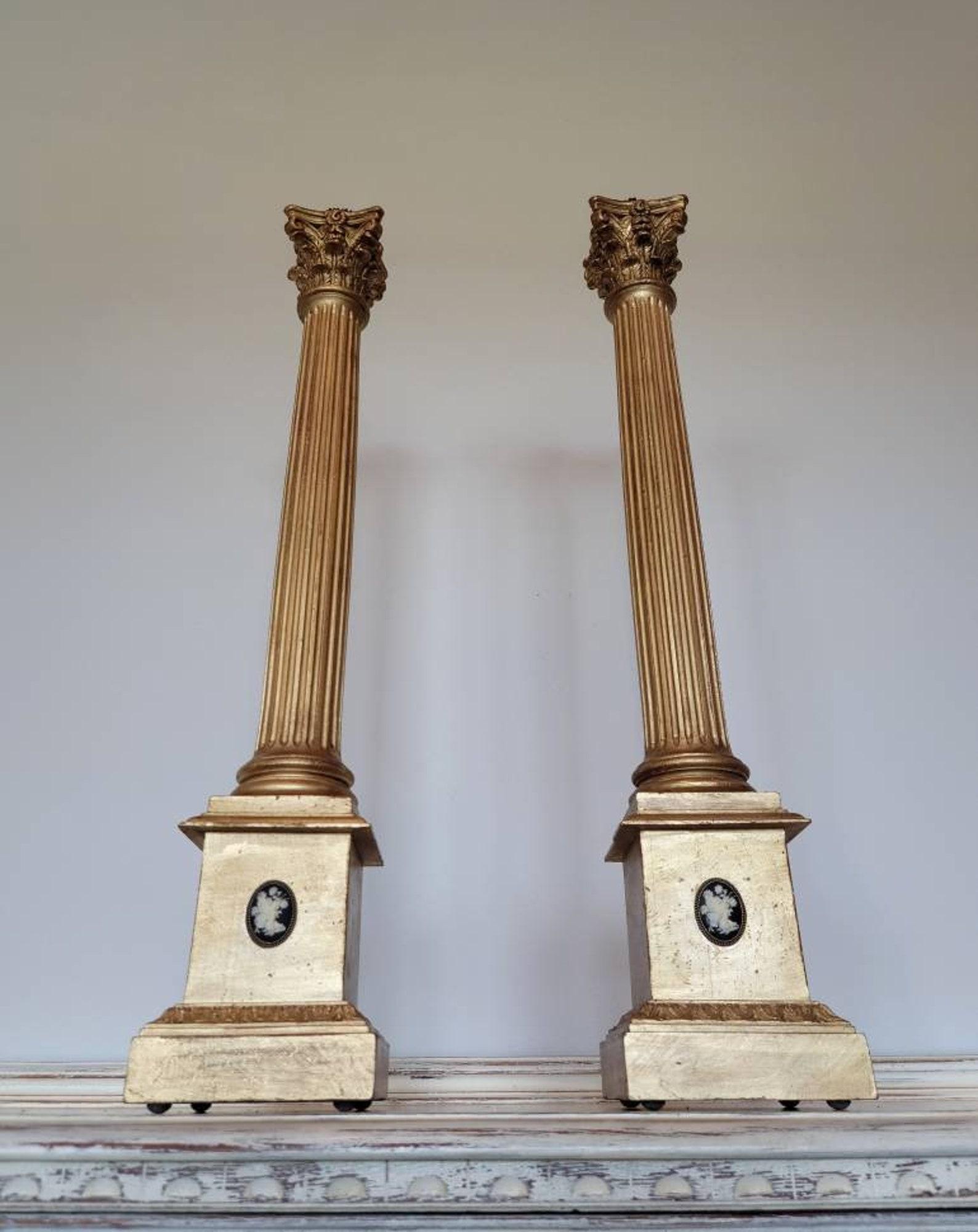 A pair of Italian Neoclassical architectural carved giltwood candlesticks with cameo mount.

Hand carved in Italy, featuring a sculptural corinthian capital with ornate scrolling volutes and acanthus leaf ornamentation, surmounted with shaped