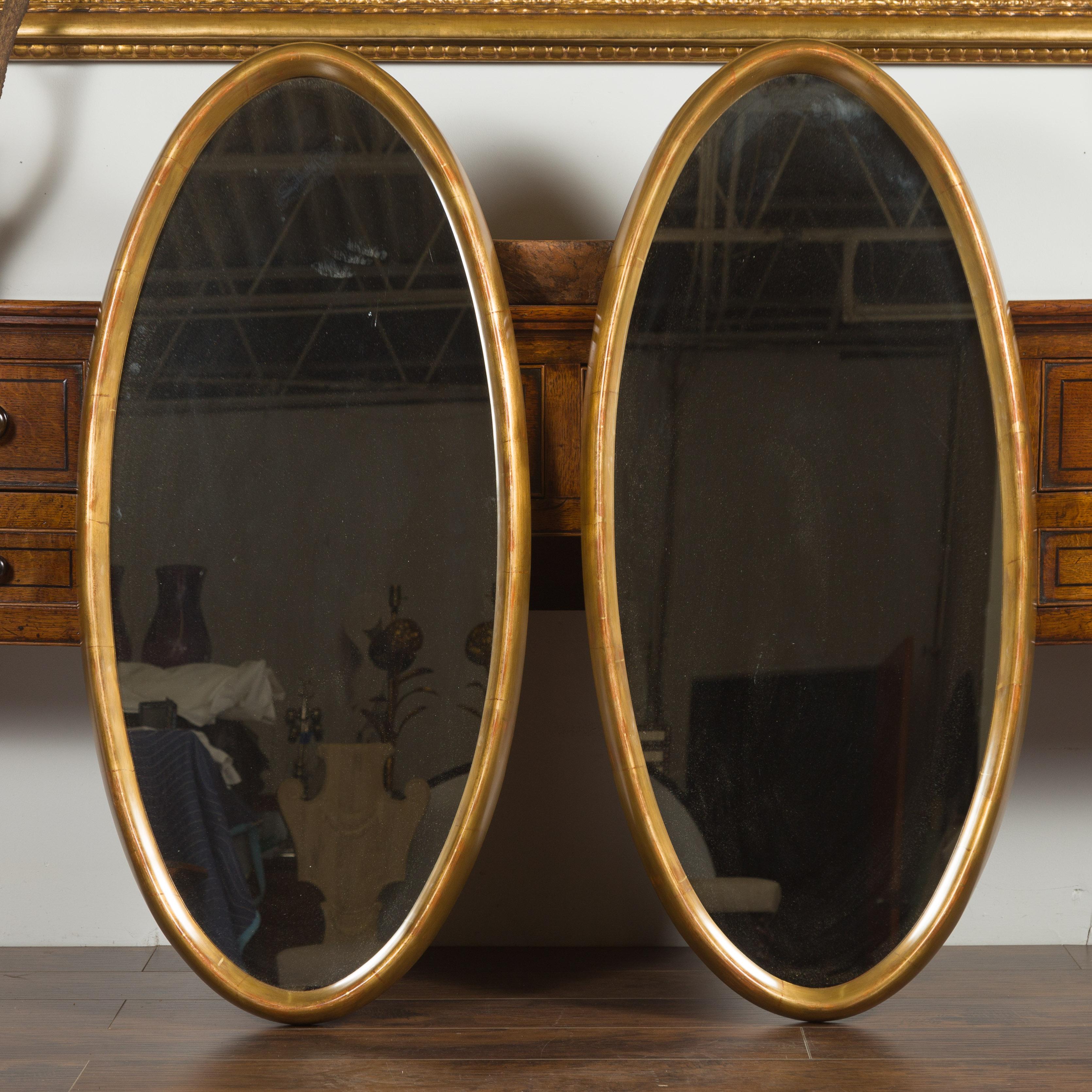 Mid-Century Modern Paire de grands miroirs ovales italiens du milieu du siècle dernier en bois doré aux lignes épurées en vente