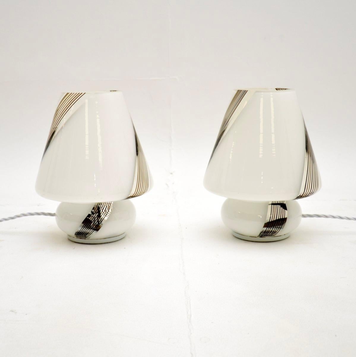 A gorgeous pair of vintage Italian Murano glass table lamps, dating from the 1970-80’s.

They are beautifully designed and are incredibly stylish. They have a mushroom shape, they are quite petite and are made from white glass, with clear, gold and
