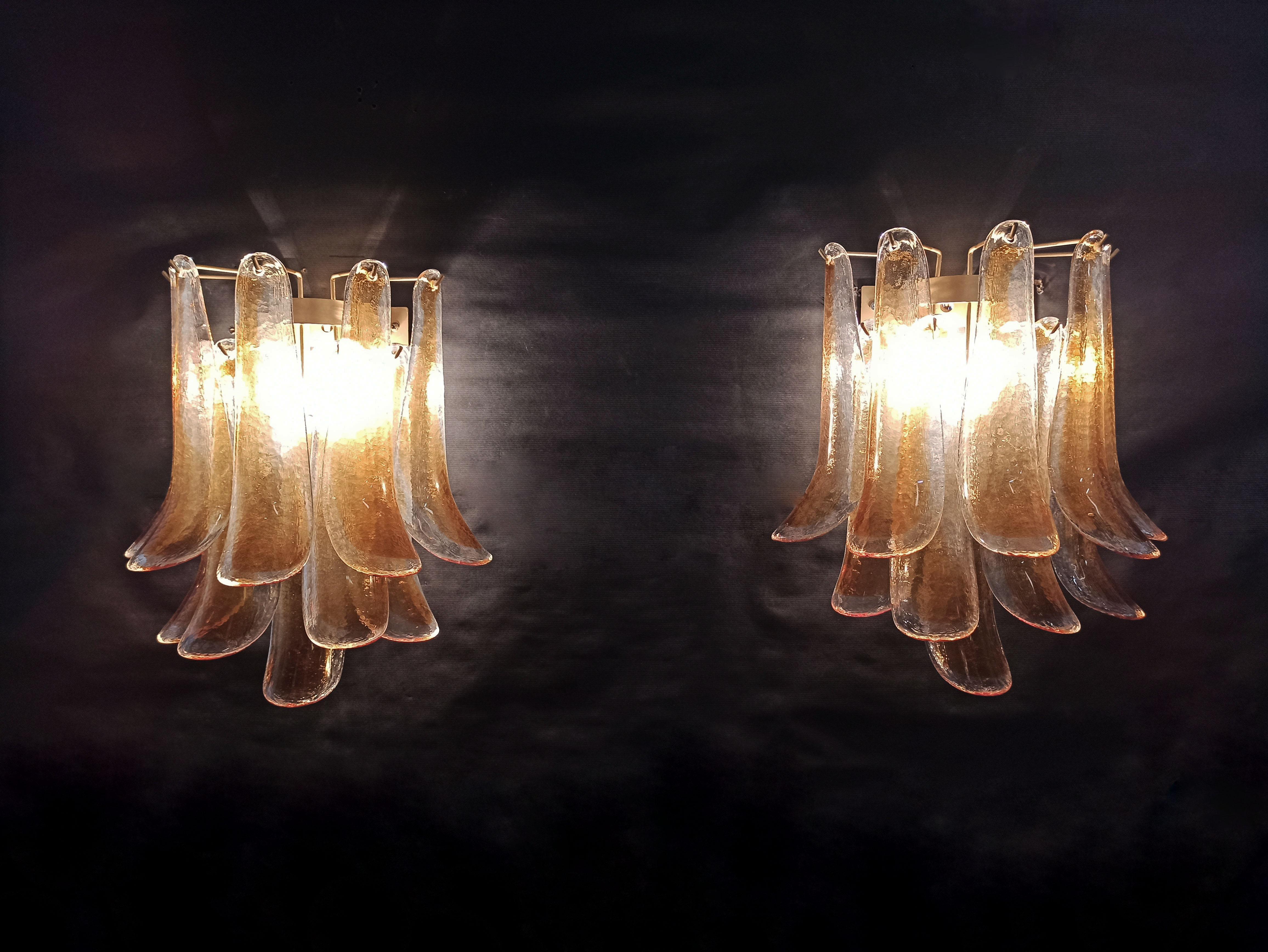 Pair of vintage Italian Murano appliques in the manner of Mazzega. Wall lights have 10 glass petals (for each applique) in a gold painted structure. The glass is transparent with an amber spot inside.
Period: late 20th century
Dimensions: 16.50