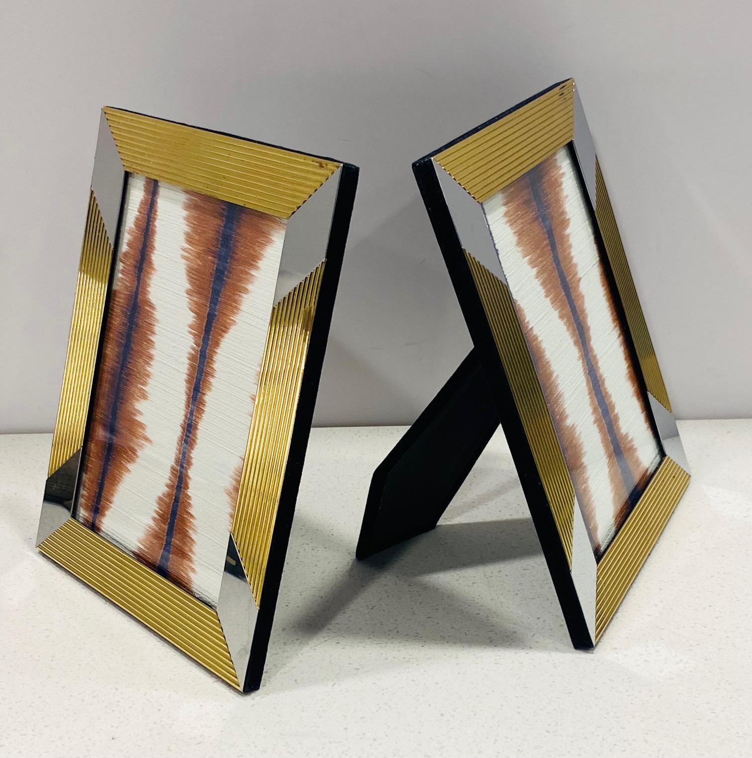 Mid-Century Modern solid brass pictures frames with geometric design. Hand polished and lacquer coated frames featuring fluted metal in gold with chrome bands, and black velvet backing. The frames are 8.75