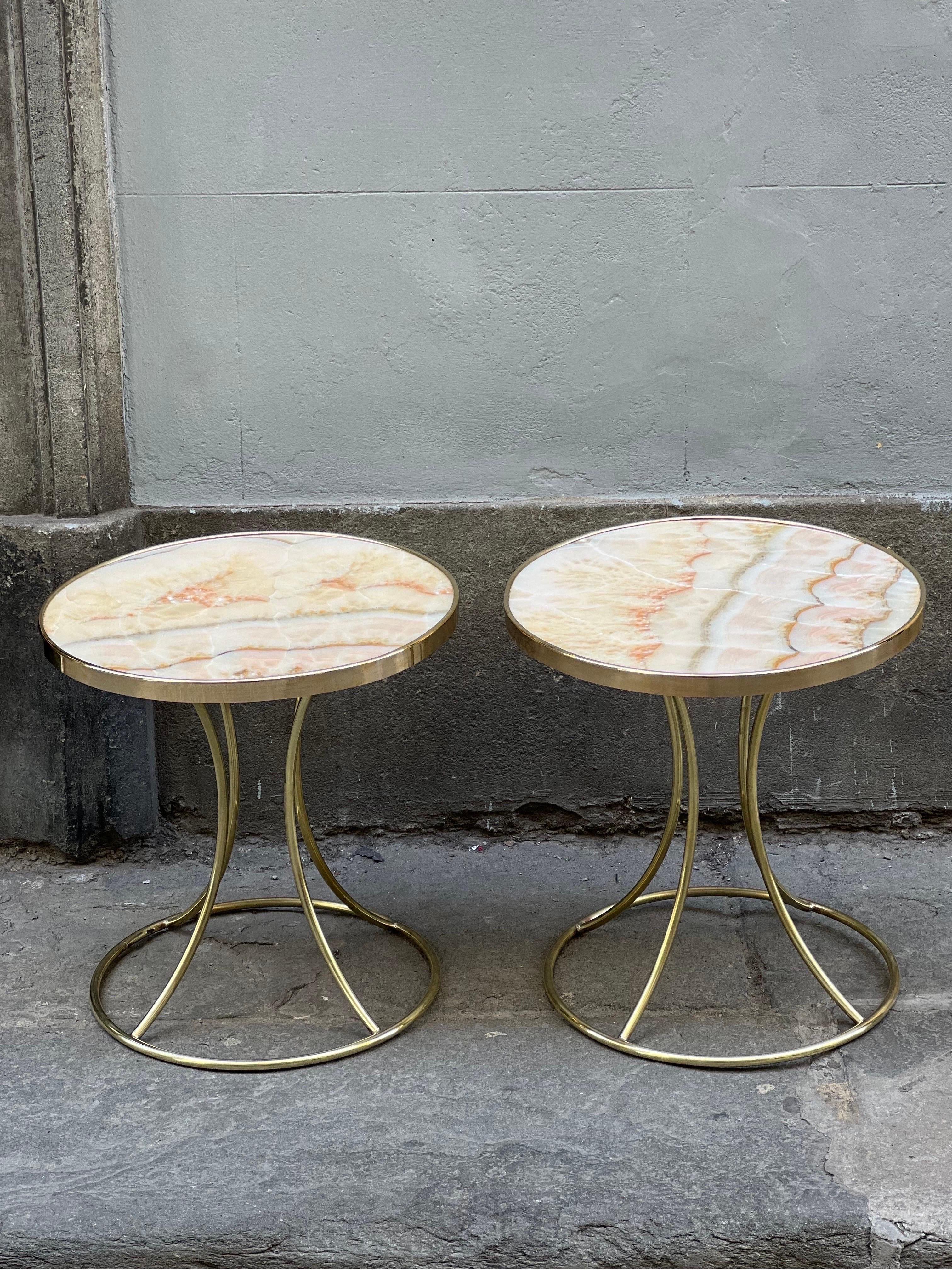 Pair of vintage Italian pink onyx and brass end/side tables. 
The round top is made of pink onyx with green and orange veins. 
The onyx top has a brass frame and the legs of the tables are made of brass.