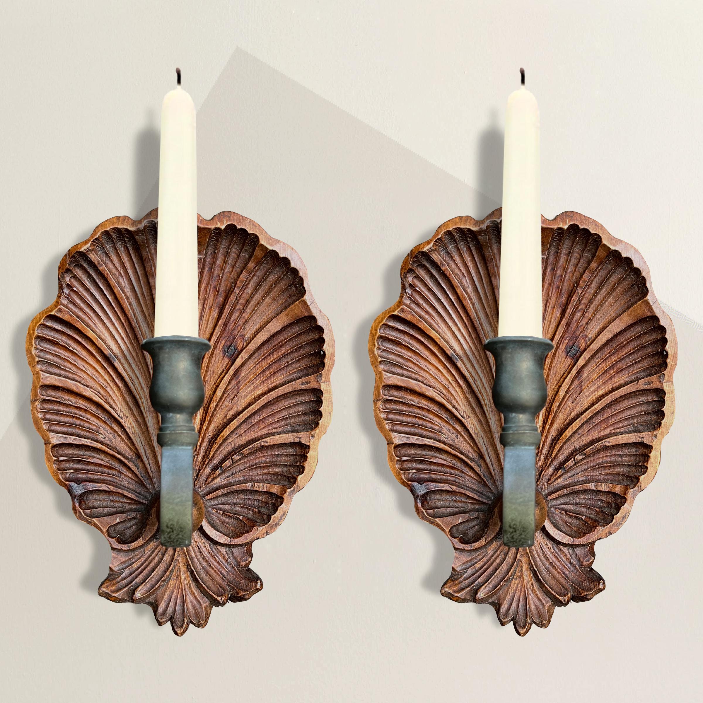 A flirtatious pair of vintage Italian hand carved walnut candle sconces with large shell backplates and brass arms and candle-cups. Perfect flanking a mirror in your entry or hung next to your bathtub allowing you to live out all of your mermaid