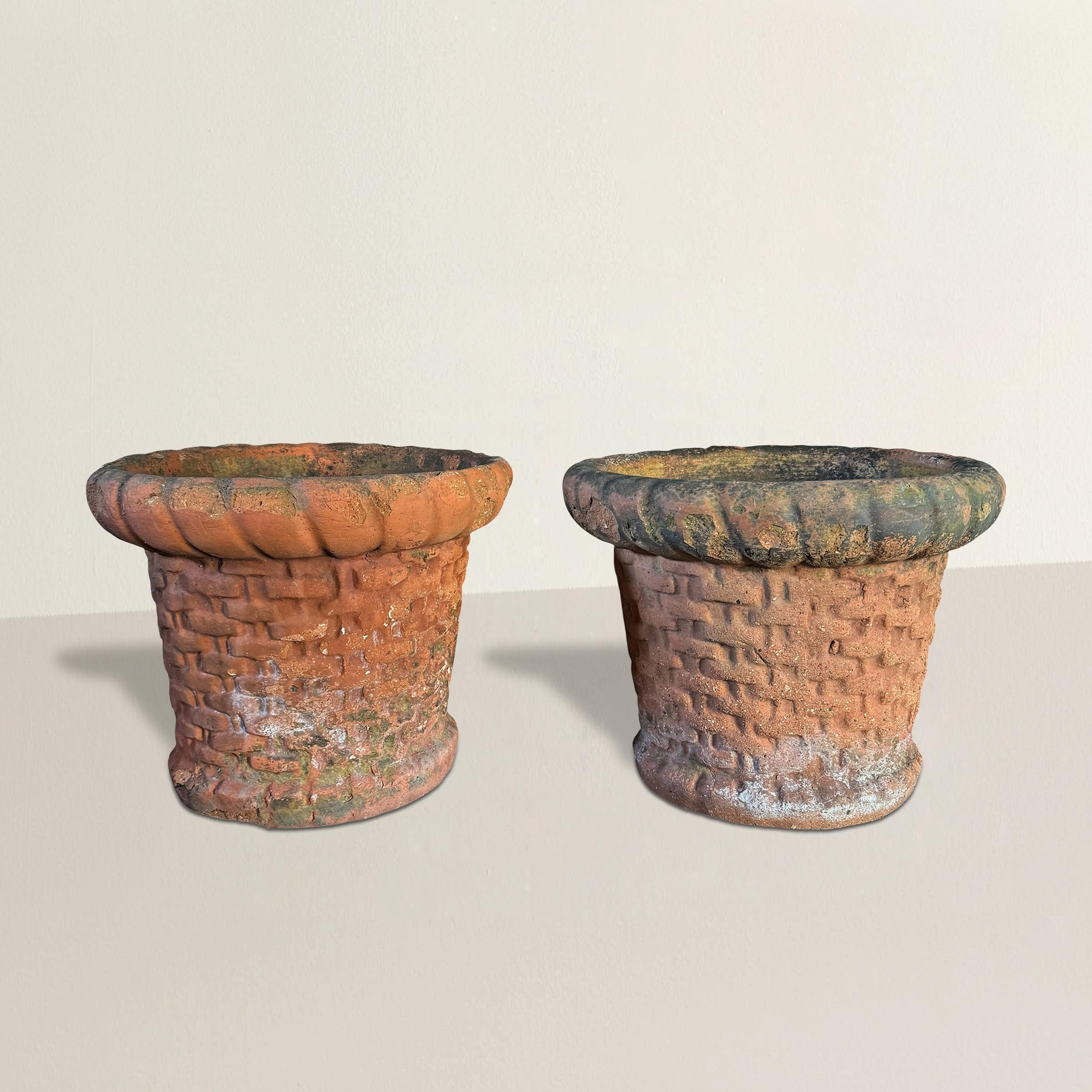 Dieses bezaubernde Paar italienischer Terrakotta-Pflanzgefäße im Vintage-Stil ist in Form von geflochtenen Körben mit dick gerollten Rändern und skulptierten Füßen gestaltet. Ihre Oberfläche ist reichhaltig strukturiert und weist eine wunderschön