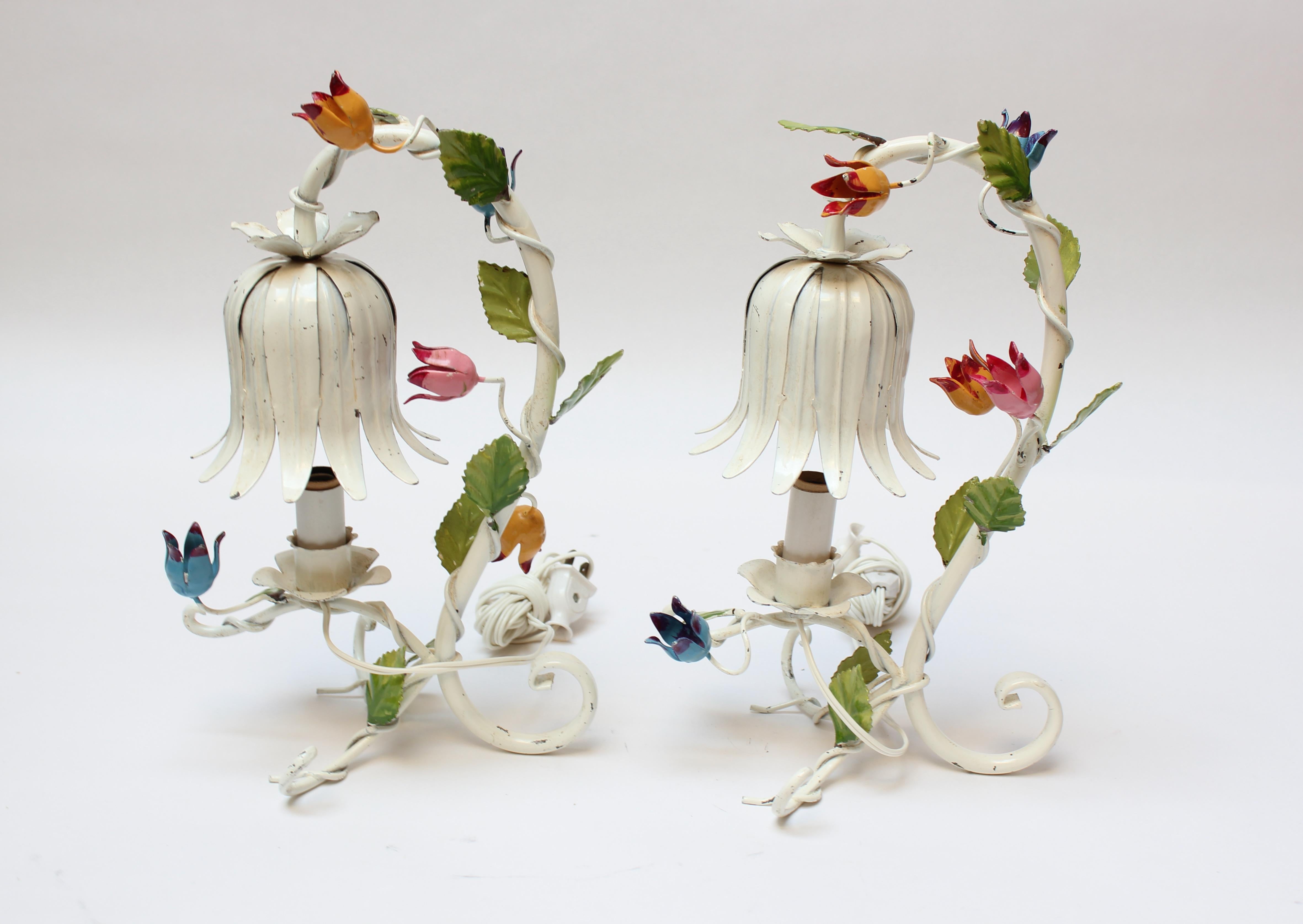Zwei kleine florentinische Tischlampen aus Keramik (ca. 1950, Italien). Bestehend aus weiß emailliertem Metall mit bunten Blumenornamenten. Originalzustand: natürliche Farbverluste und Patina. 
Leichter Höhenunterschied zwischen den beiden (12,25