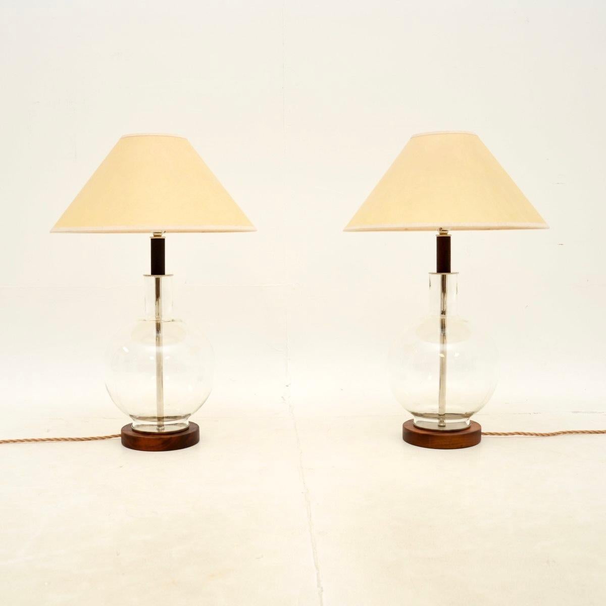 Une paire de lampes de table italiennes en noyer et verre, très élégante et bien faite, datant des années 1970.

Ils sont d'une superbe qualité et ont un design magnifique, avec des cadres en verre soufflé de toute beauté. Ils reposent sur des bases