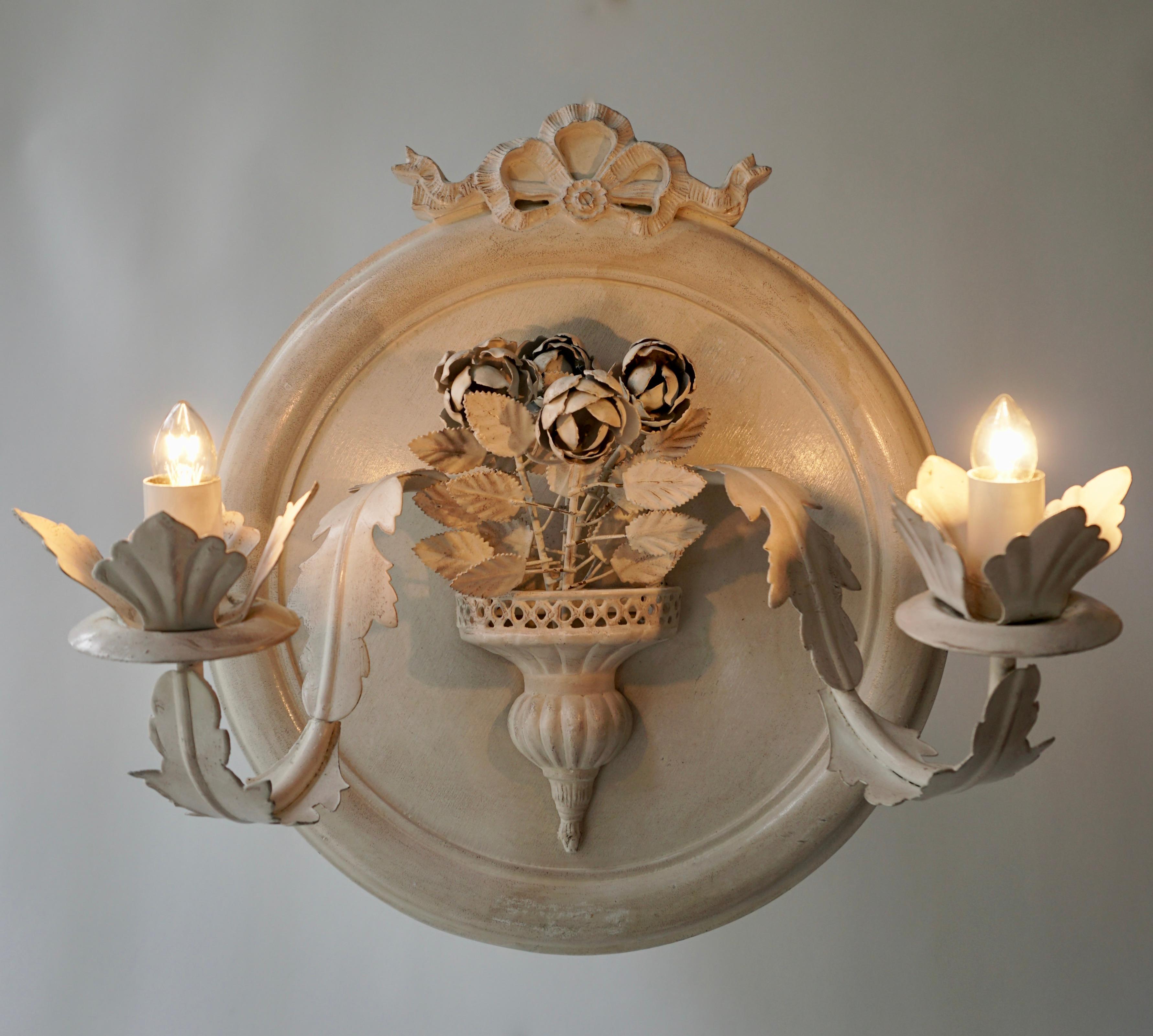 Pair of vintage Italianate white painted metal electric candle sconces, with elaborate layers of leafy and flowers on a round wooden white painted background.

Condition: Good condition with expected signs of wear.