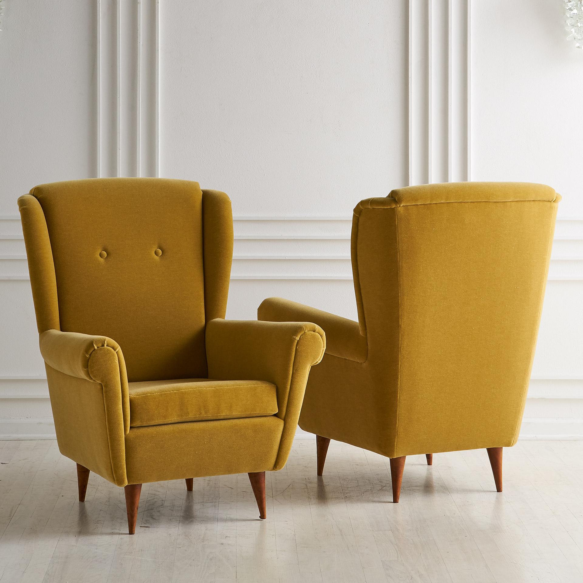 A handsome pair of midcentury Italian wingback chairs newly upholstered in a mustard yellow mohair with tapered wood legs.