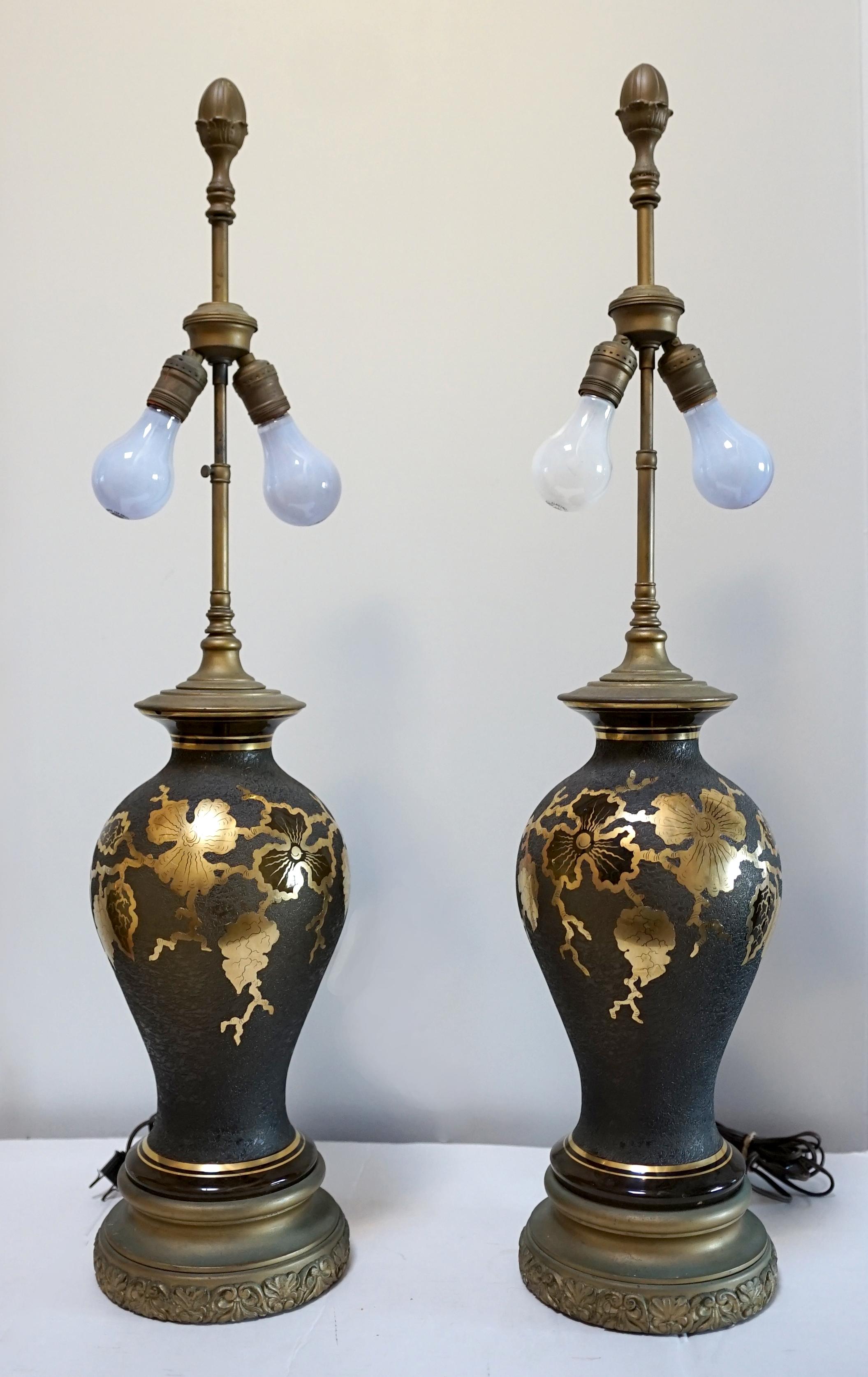 A pair of vintage Japonesque faux lacquer painted glass table lamps
mid to third-quarter of the 20th Century and stunning.
Of circular section and baluster form, with flared tops, stylized gold leaf decoration on black grounds, on circular feet.