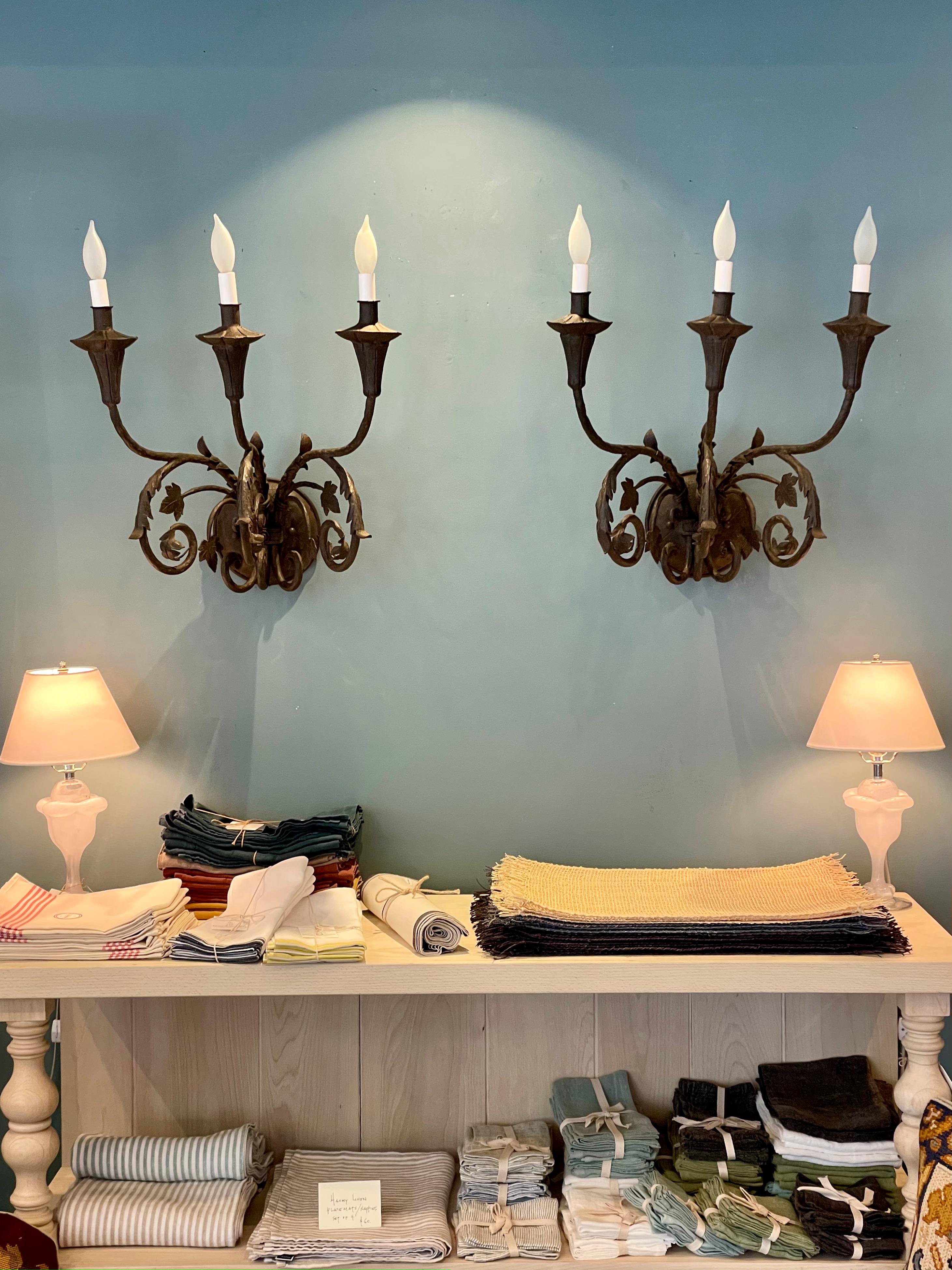 What a striking pair of large decorative vintage 3-arm iron sconces. These extraordinary floral themed sconces have an attractive new 'French Iron' finish, new wiring and are ready to adorn and light up your wall in the most dramatic fashion.

18.5