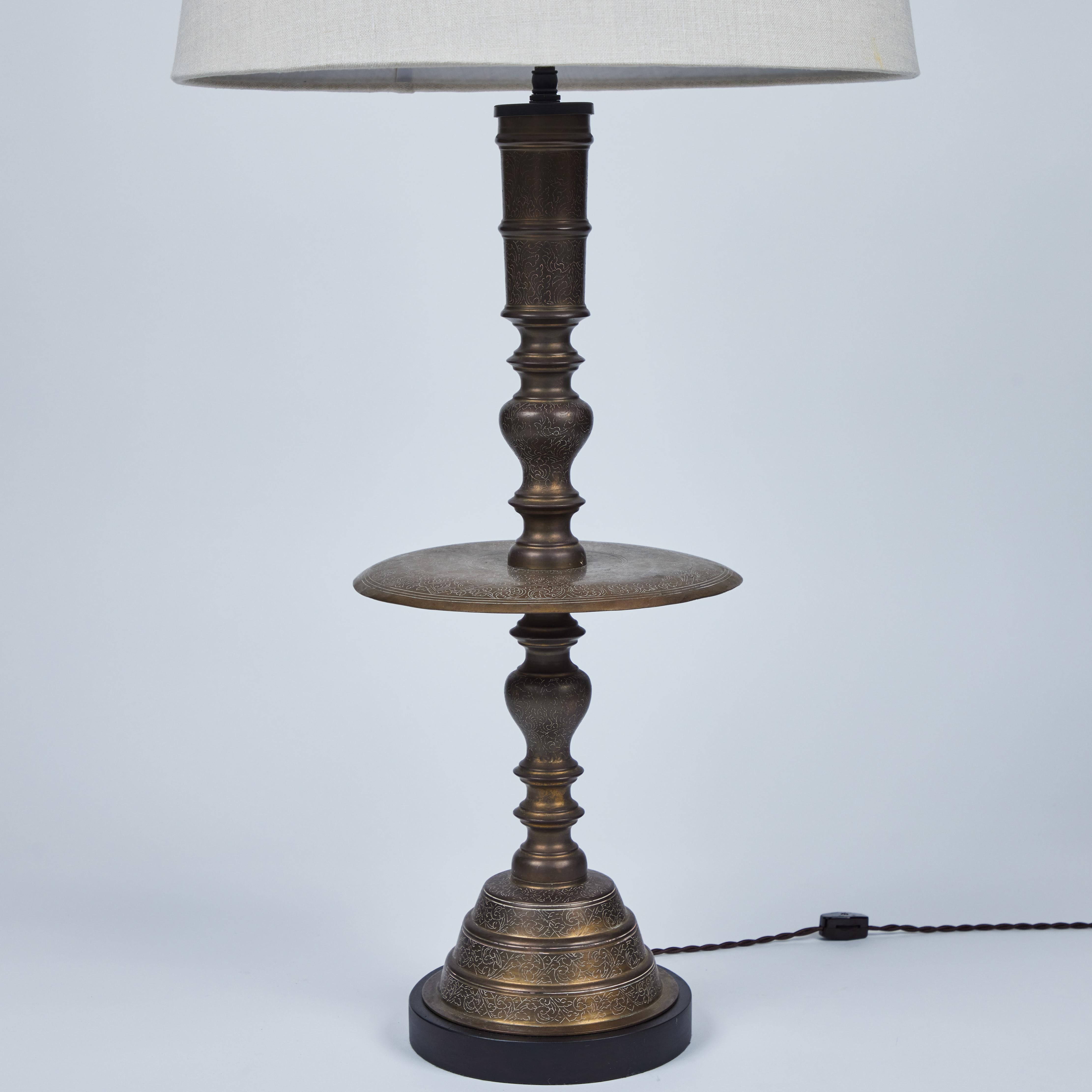 These large intricately engraved vintage brass Moroccan candlesticks with large decorative drip catcher have been newly made into this pair of striking and eye catching table lamps. They have lovely custom linen shades and beautiful new wood bases. 