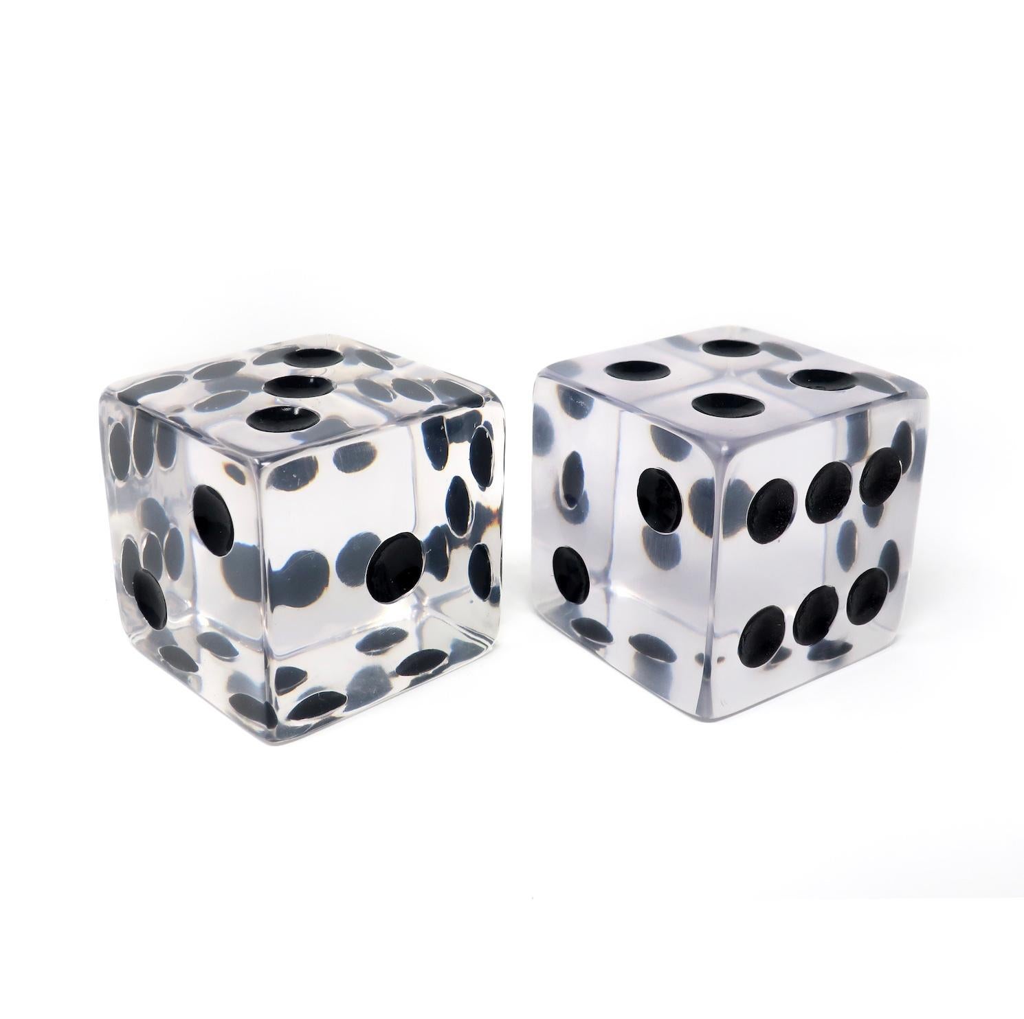 A pair of oversized Lucite dice in the style of Charles Hollis Jones. Heavy enough to use as bookends or paperweights and striking enough to be a lovely decorative object. Clear acrylic with black dots.

In very good vintage condition with light