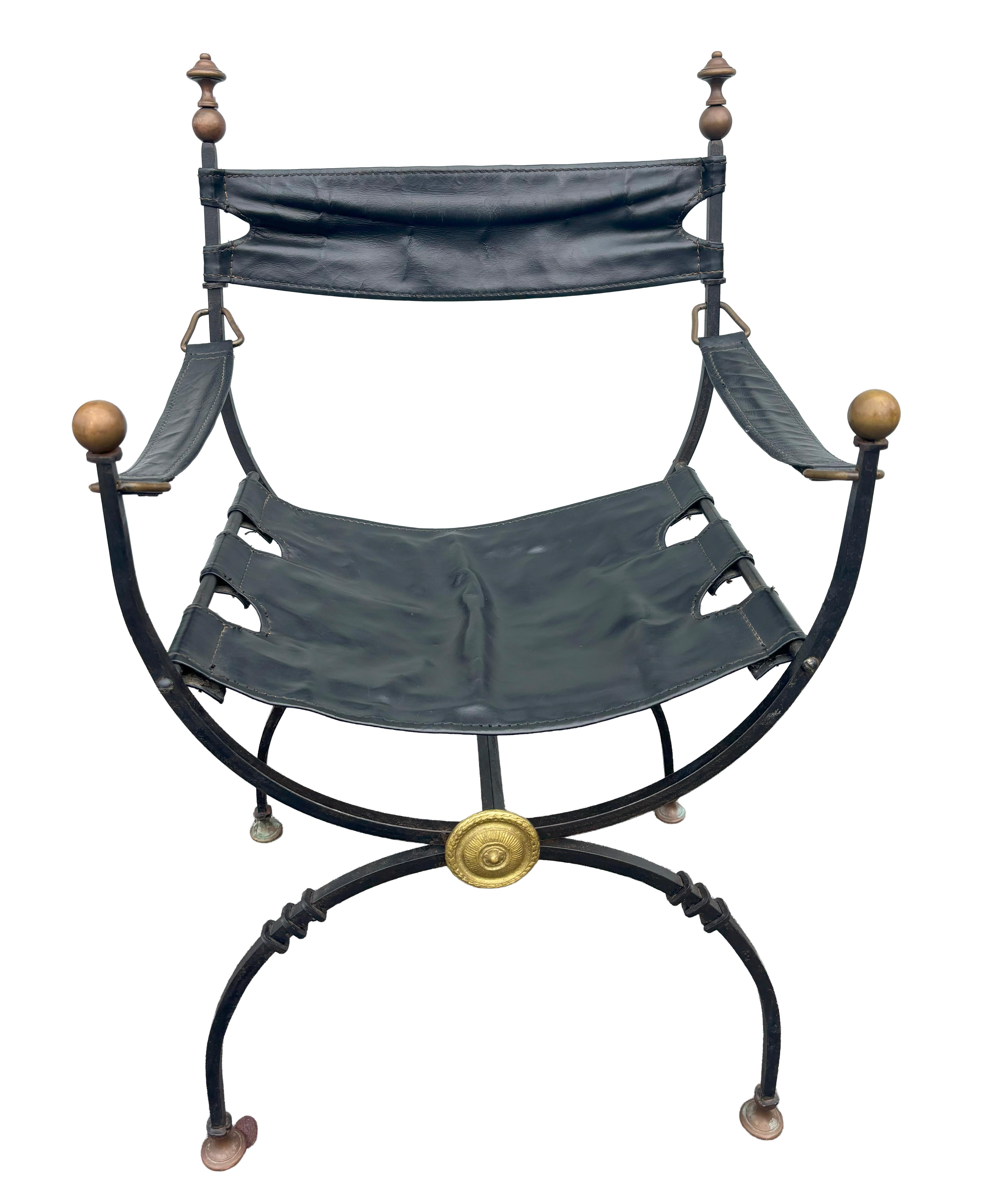 Forma de silla de director con remates de latón en el respaldo. Remates de latón en los extremos de los brazos. Cuero negro.