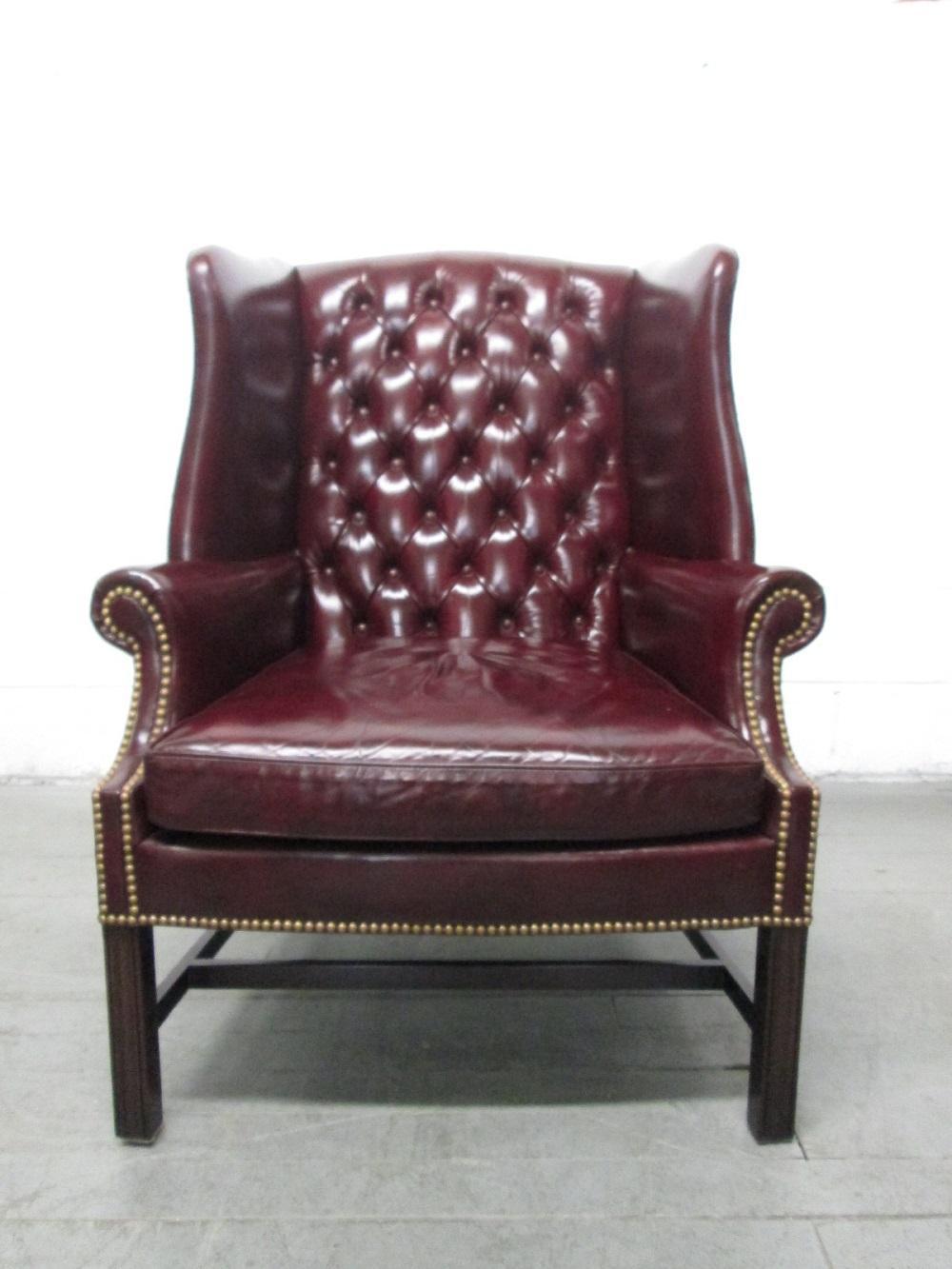 Pair of burgundy leather tufted wingback chairs. Has brass studs, 