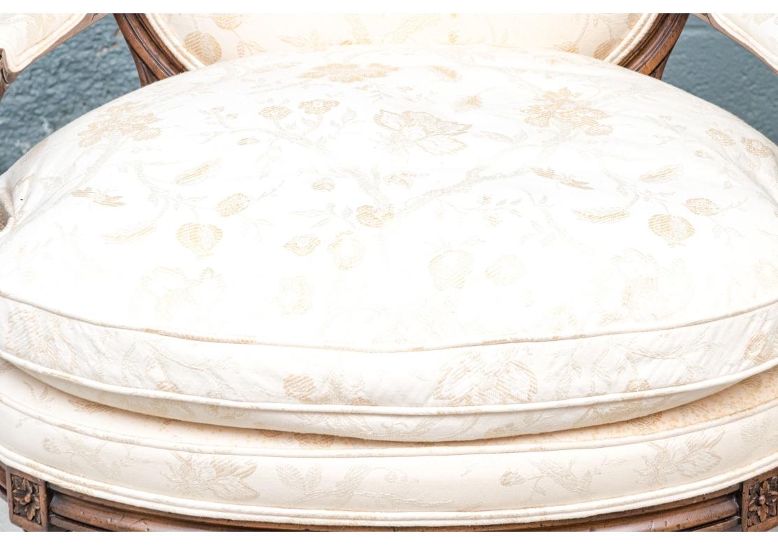 Das Paar eleganter Fauteuils hat niedrige, ovale Rückenlehnen und geschnitzte, geriffelte und verschnörkelte Armenden auf sich verjüngenden Stützen mit kannelierten Basen. Die breiten ovalen Sitze stehen auf kannelierten, spitz zulaufenden Beinen