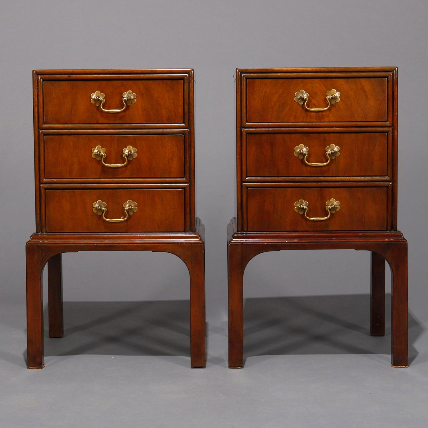 A vintage pair of Chinese Chippendale stands by Kittinger each offer mahogany construction with case having three drawers having pulls with flower form escutcheons, raised on squared and straight legs, marked on drawer interior as photographed,