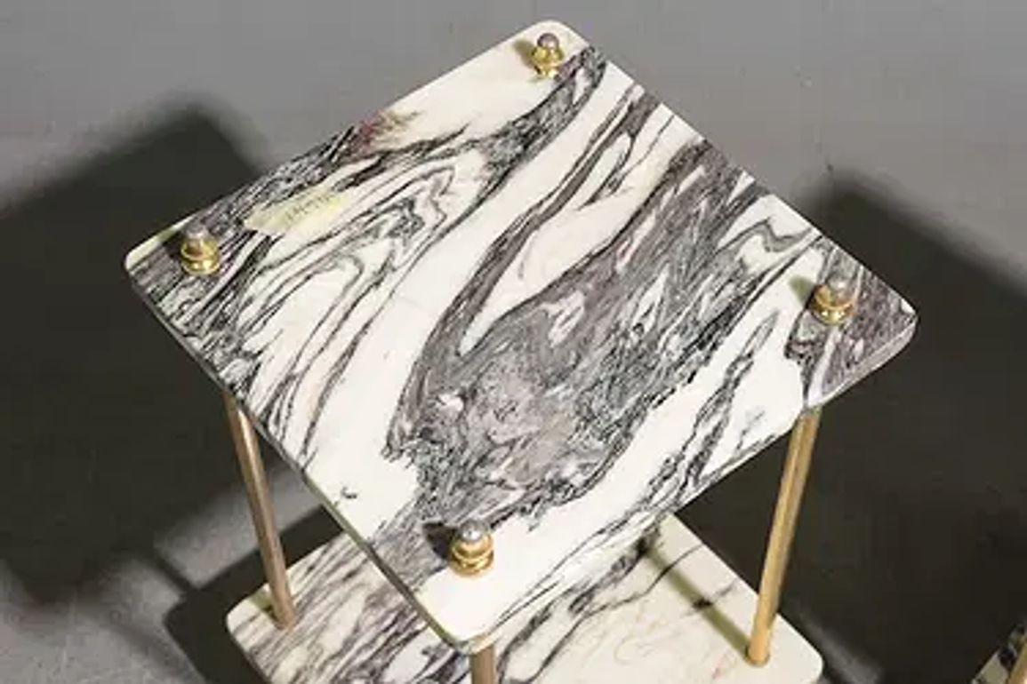 The product is a pair of  Maison Jansen style  brass and breccia marble side tables. The tables have a very sleek look with a marble tabletop and brass legs, adding a touch of elegance and sophistication to any room. These tables a timeless and