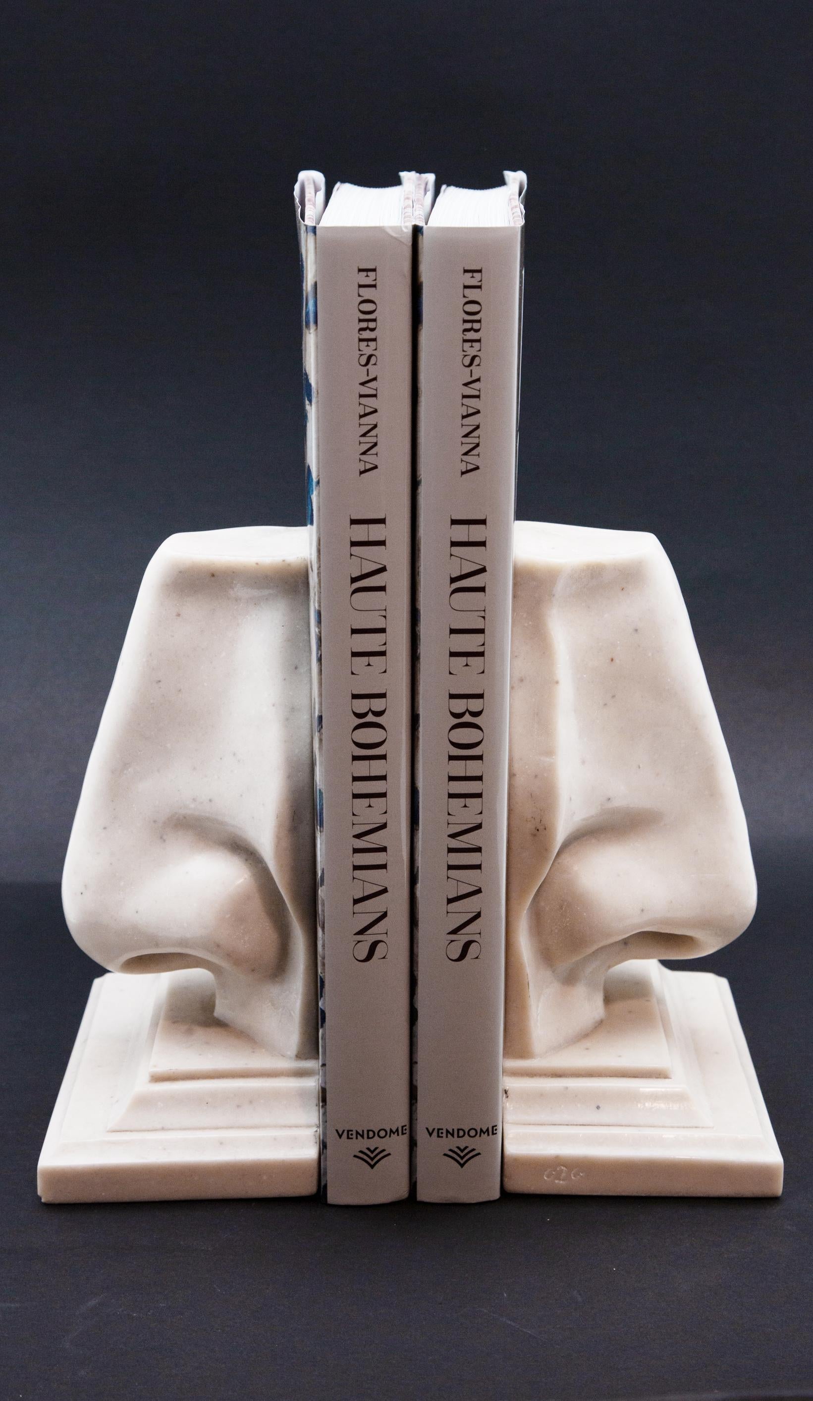 Pair of nose-shaped bookends. Made from resin that appears like white marble. 8.75 inches tall, 6.25 inches wide, 3.75 inches deep.