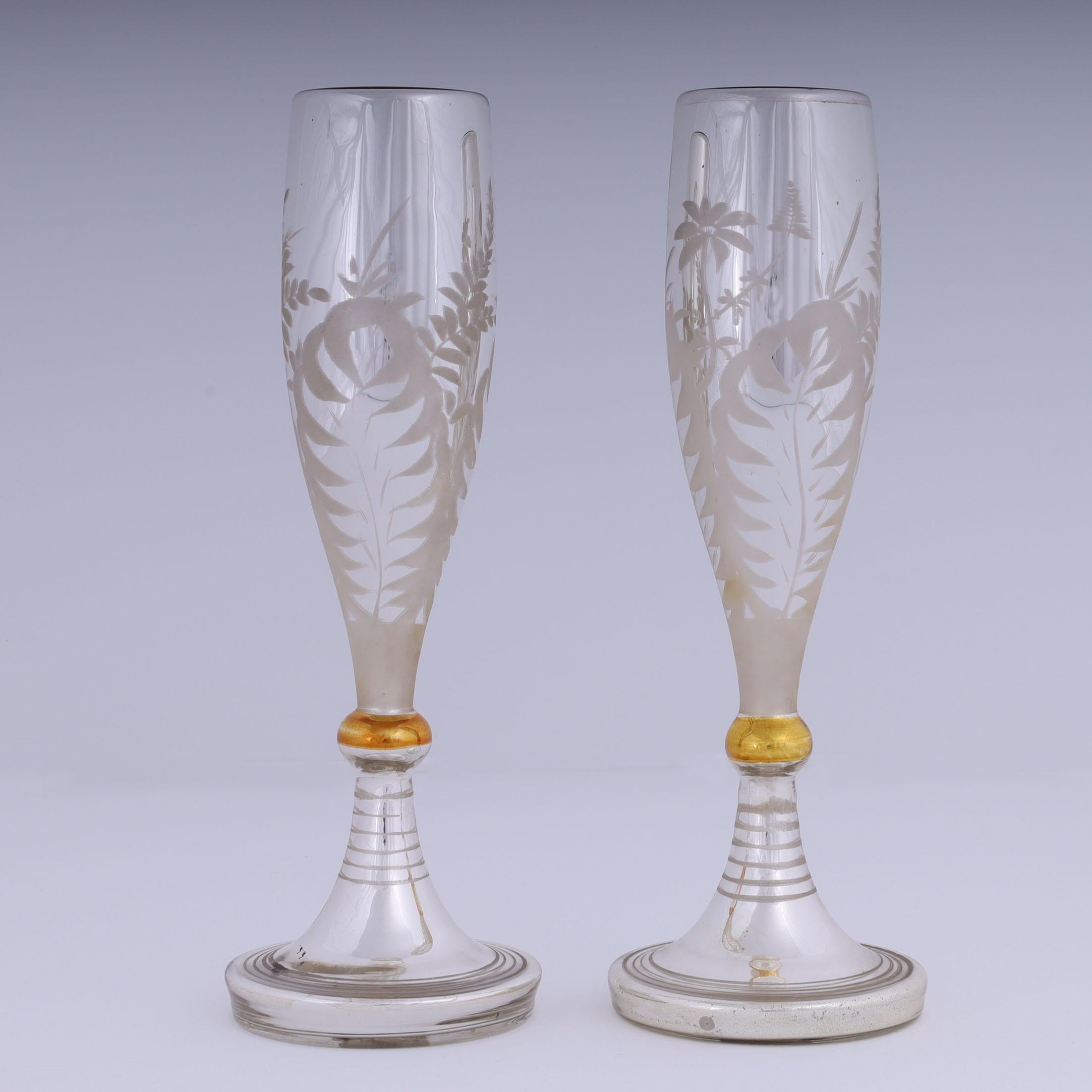 Ein Paar mundgeblasene Quecksilberglasflöten aus der Mitte des Jahrhunderts in klassischer Champagnerglasform, verziert mit geätzten Blumen und Farnen auf den Außenseiten und goldfarbenen Innenseiten, signiert Haida Bohman auf den Böden.
