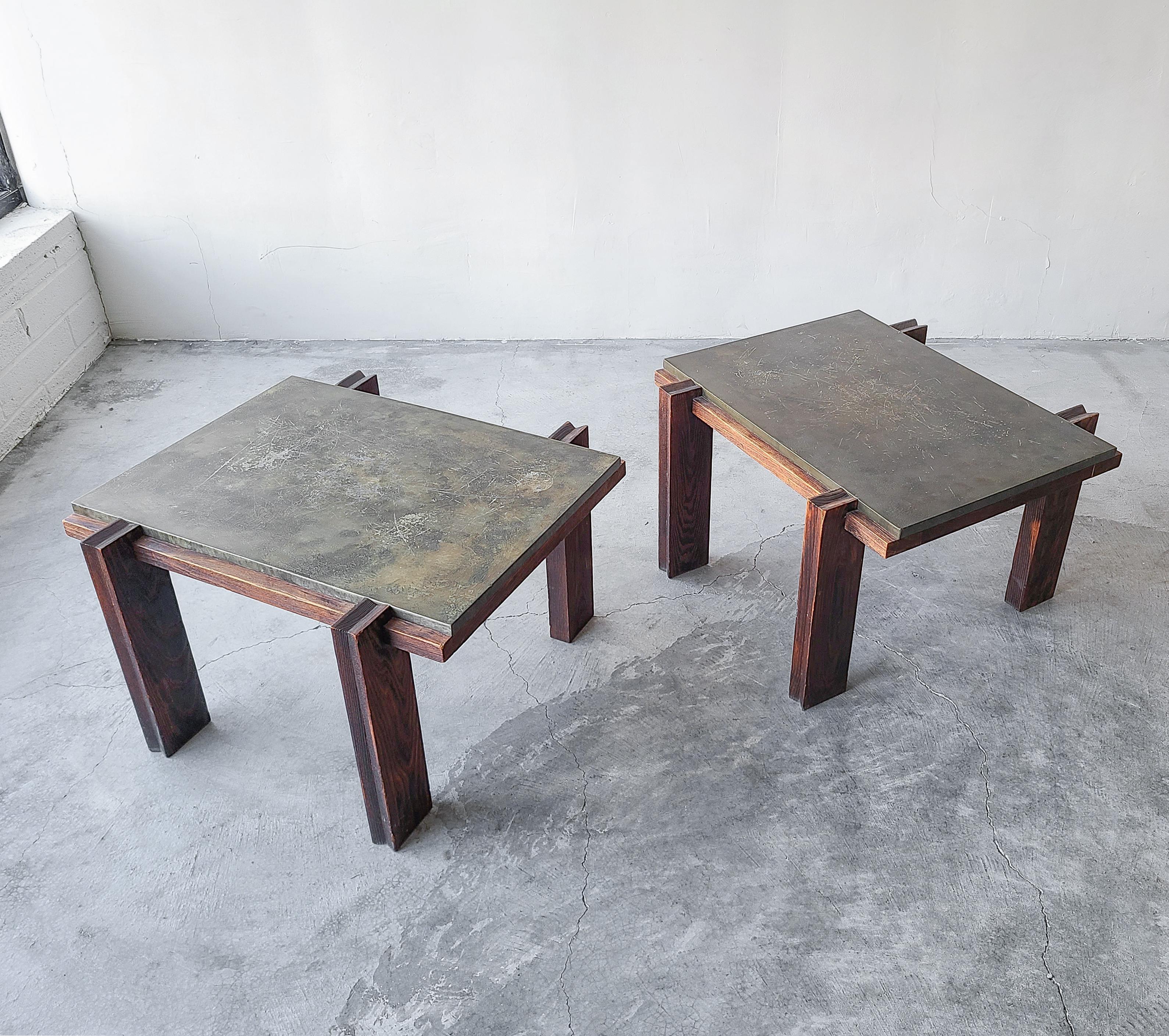 Very unique vintage pair of aged metal and darkened oak side tables. Tables are architecturally interesting with unique carved wood details, very craftsman style feel.

Tables are structurally sound. Metal tops show some wear to the metal adding a