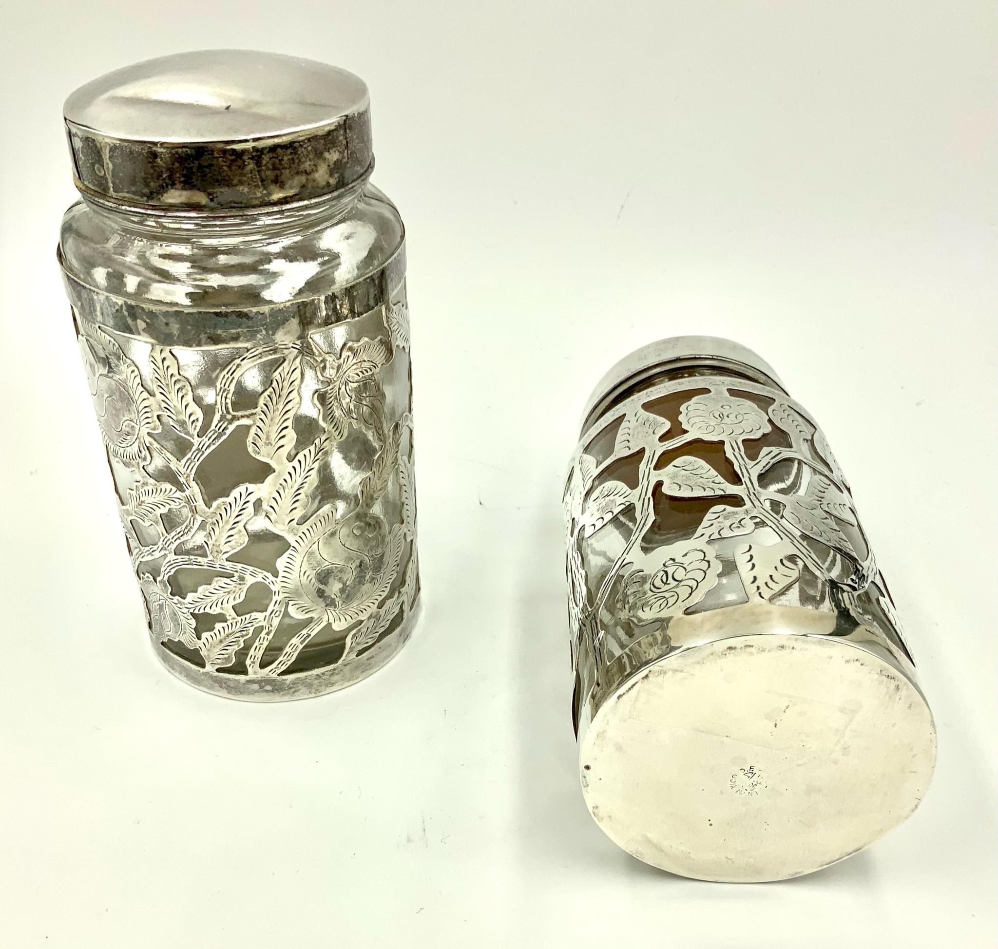 Pair of vintage Mexican etched floral sterling overlay glass jars with simple sterling screw on caps. These wonderful jars were produced in Mexico and feature a wonderful sterling overlay sleeve with an engraved floral flower and leaf design. The