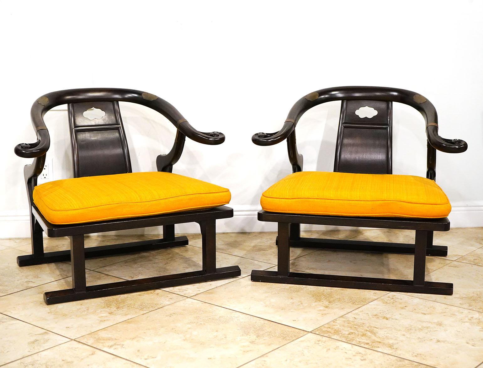 Pair of Chinese Style lounge chairs by Baker Furniture and designed by Michael Taylor. Dark Brown wood with brass accents. Labeled on bottom. Horseshoe design.