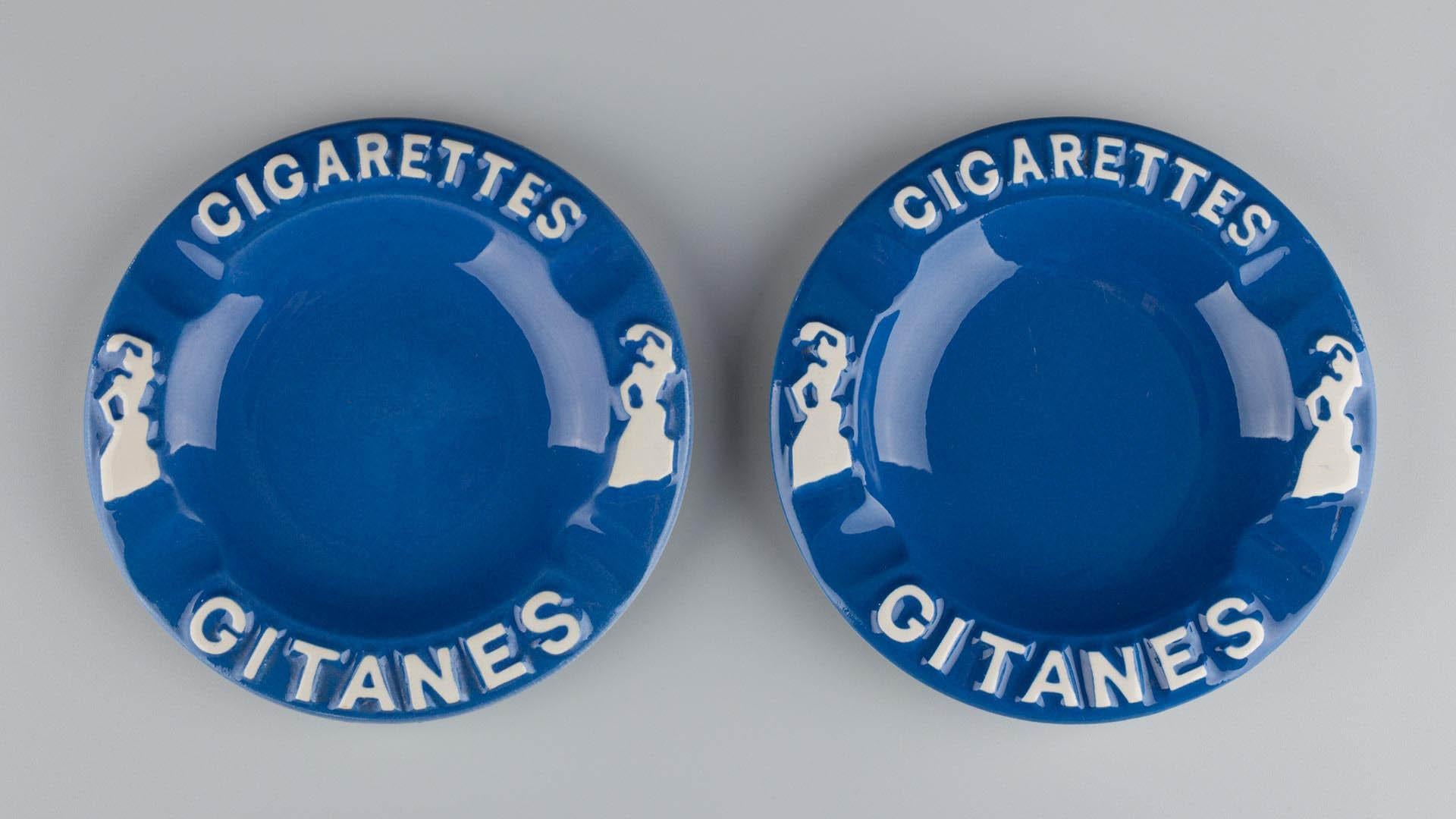 Pair of Gitanes Ashtrays

France
Glazed ceramic
circa 1950–1970

Dimensions:
H × W: 2 × 14 cm

Description:
This pair of vintage advertising ashtrays is made of white glazed ceramic and bears the iconic “GITANES” logo. The circular shape features