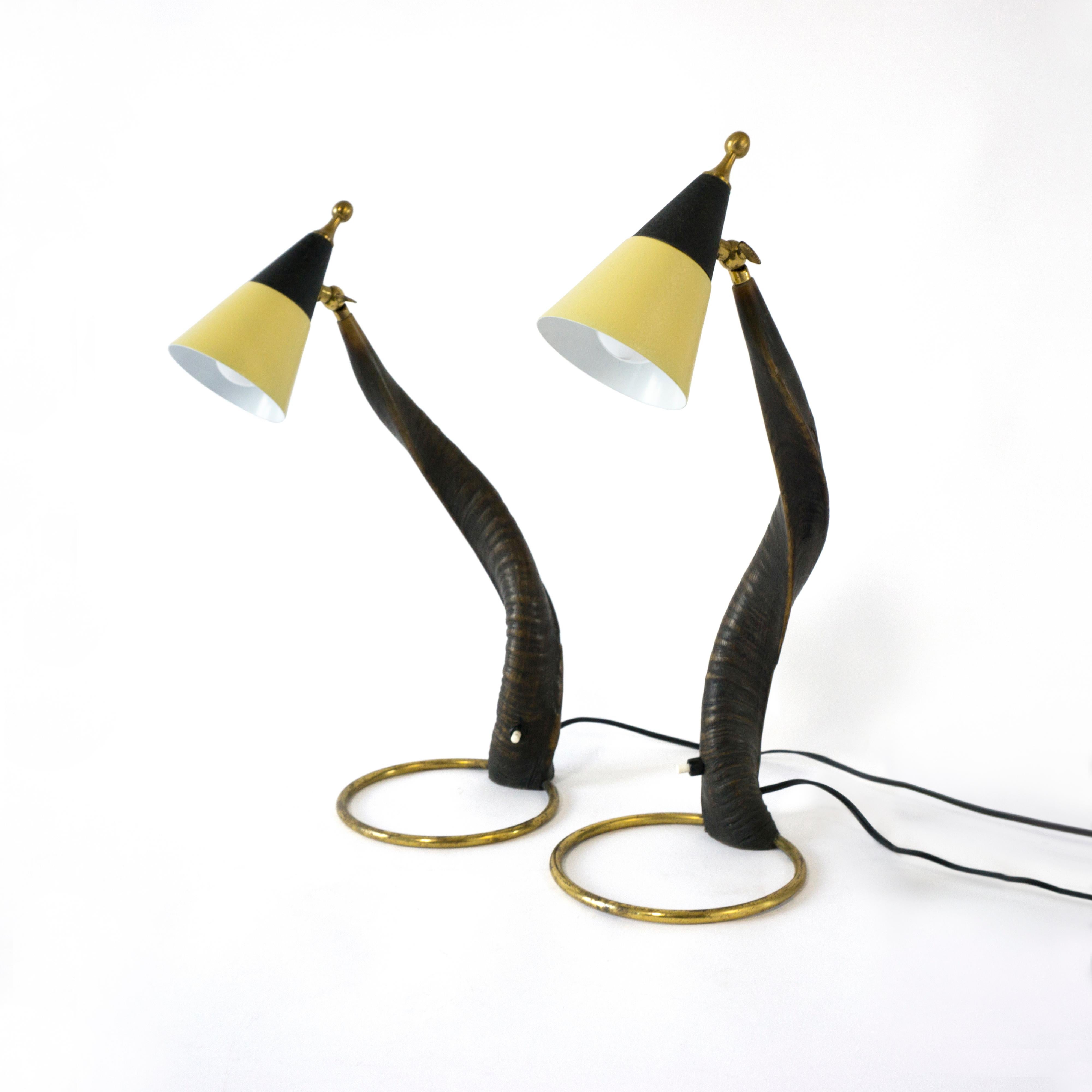 The beautifully grown, twisted horn forms the base of these exceptional table lamps from the 1950s. 
The curved horn sits on a lovely patinated brass ring. The lamps are equipped with an on/off switch, which is located in the horn. The shades made