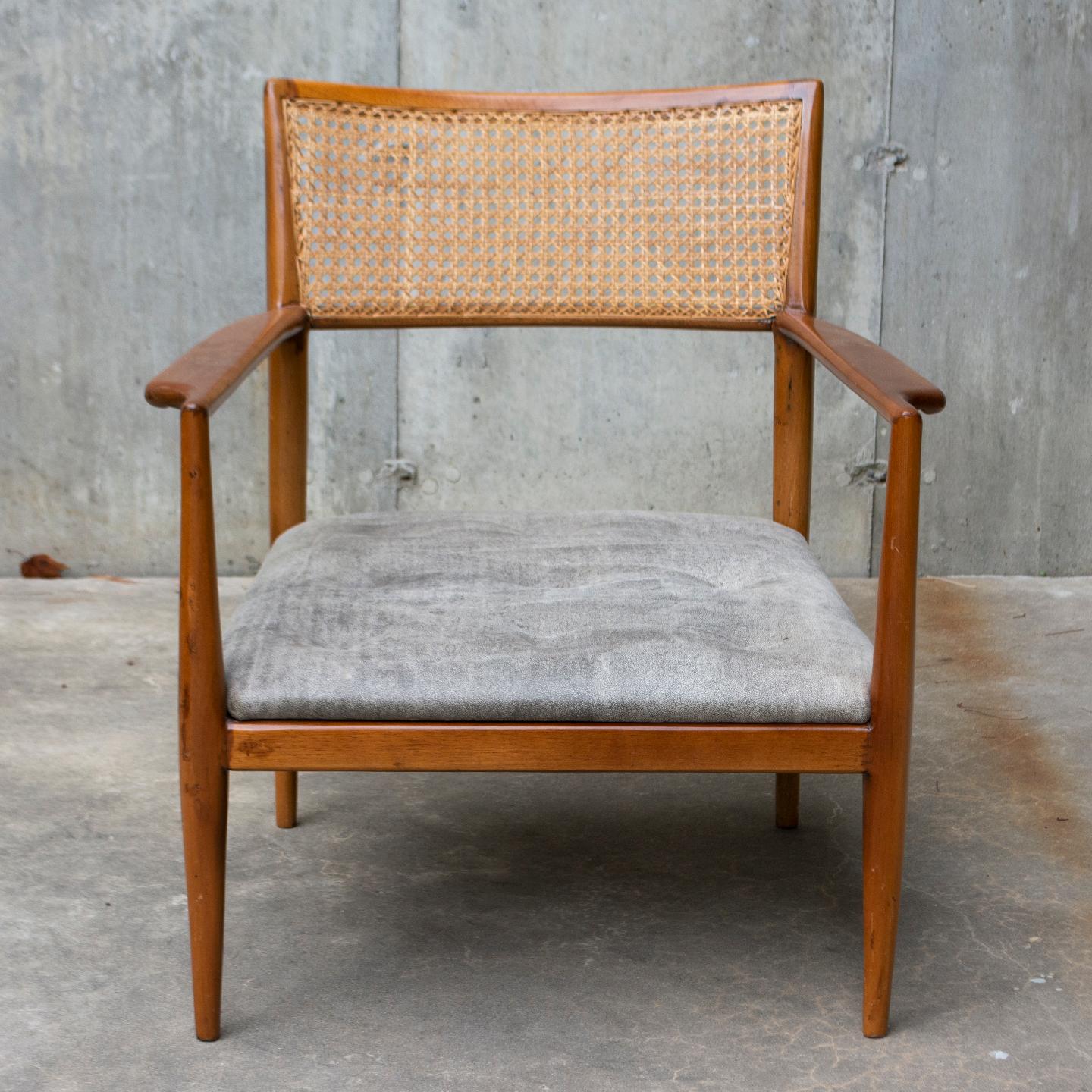 The warm brown color of this chair’s slender frame beautifully complements the cool gray upholstery of the tufted seat. Carved from rosewood, the chair boasts gracefully carved arm rests, classic rattan back, and toothpick legs, a hallmark of modern