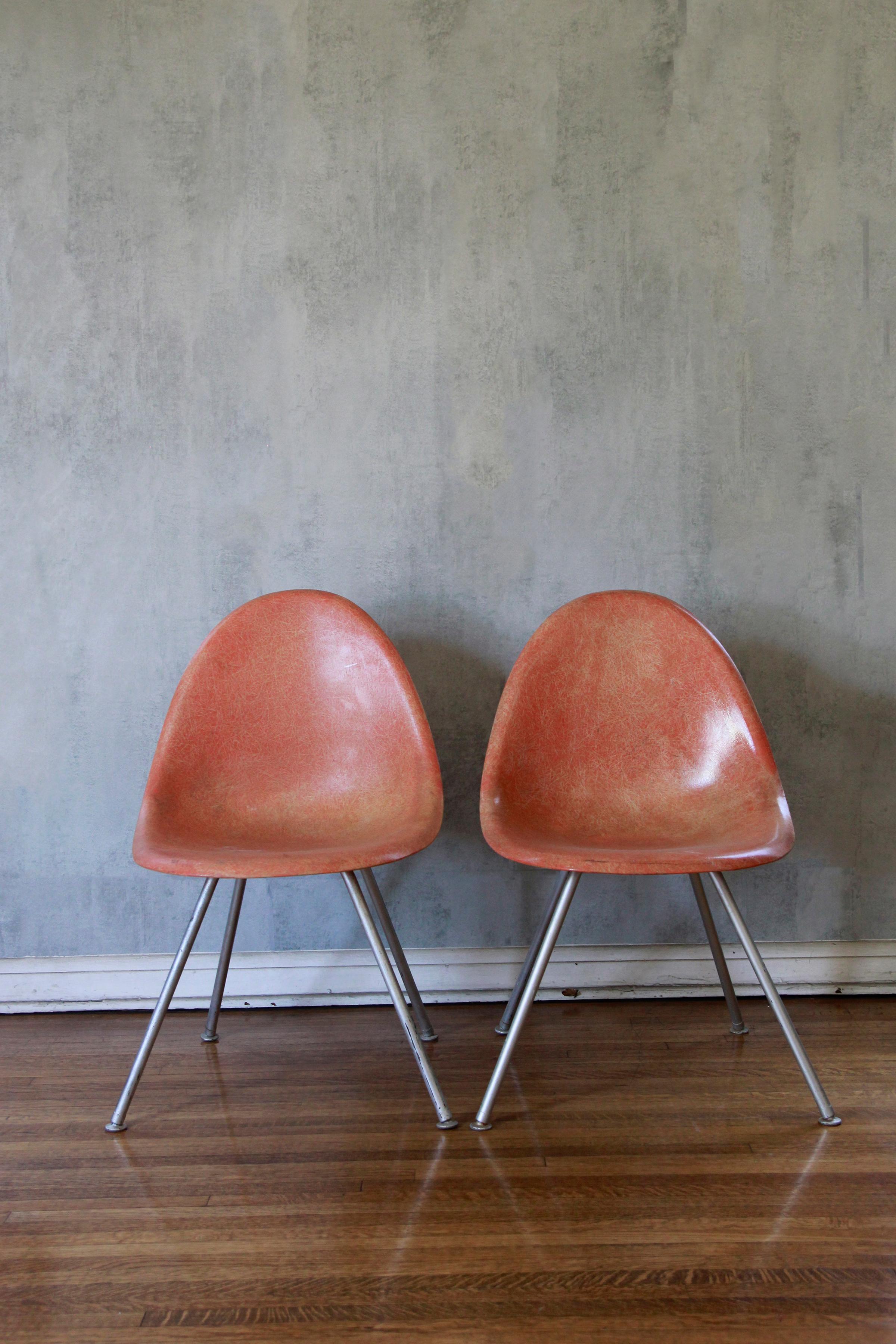 Fiberglass shell chairs circa 1960 salmon color chairs 
Iconic design with fiberglass shell on stackable steel base. 
Comfortable contoured ergonomic design. 
Embossed number on both under the chairs. 
Iconic and collectible chairs and mid century