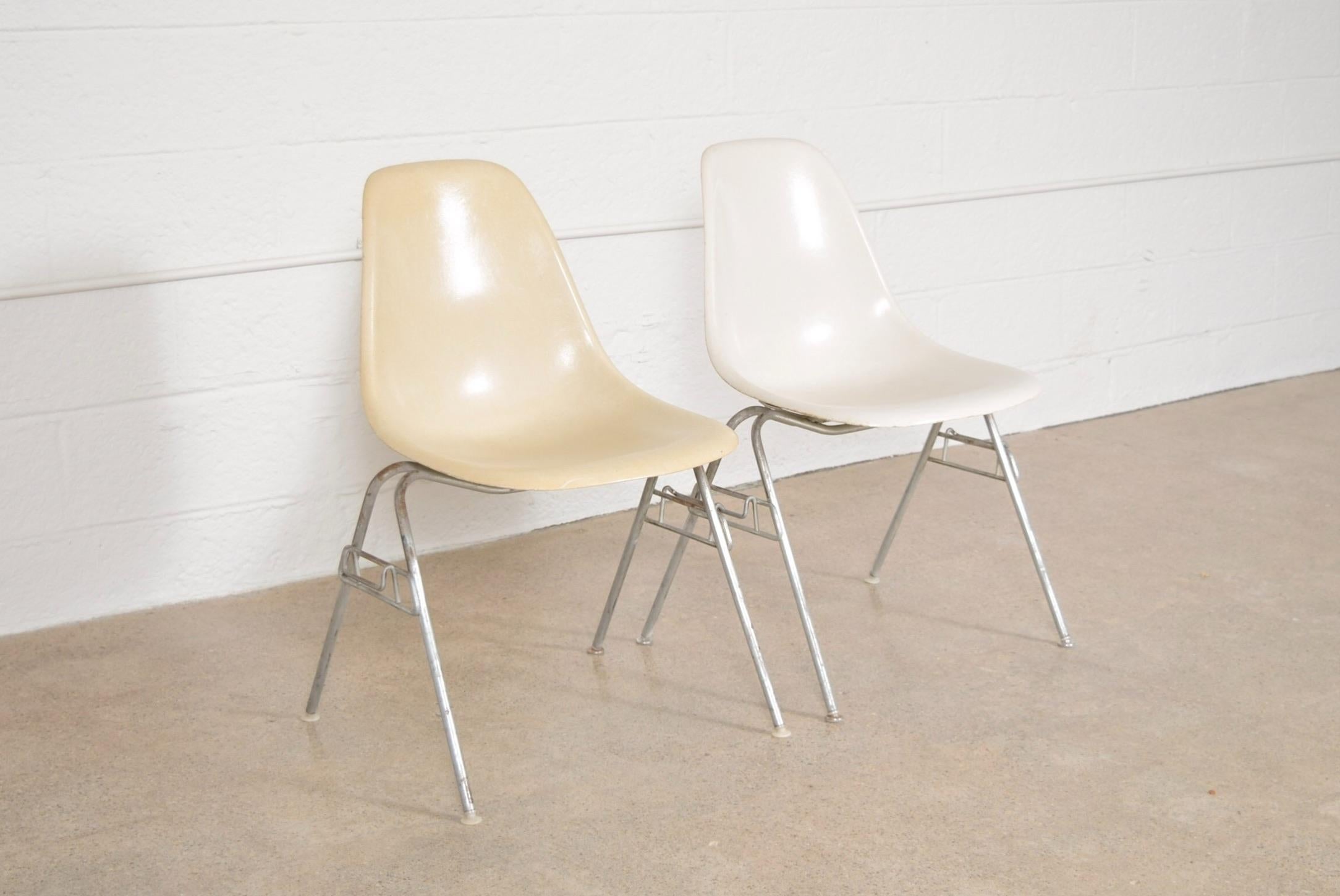 • Original Eames Herman Miller DSS fiberglass shell chairs circa 1960. One bone and one white chair.
• Iconic design with fiberglass shell on stackable steel base.
• Comfortable contoured ergonomic design.
• Herman Miller embossed stamp on
