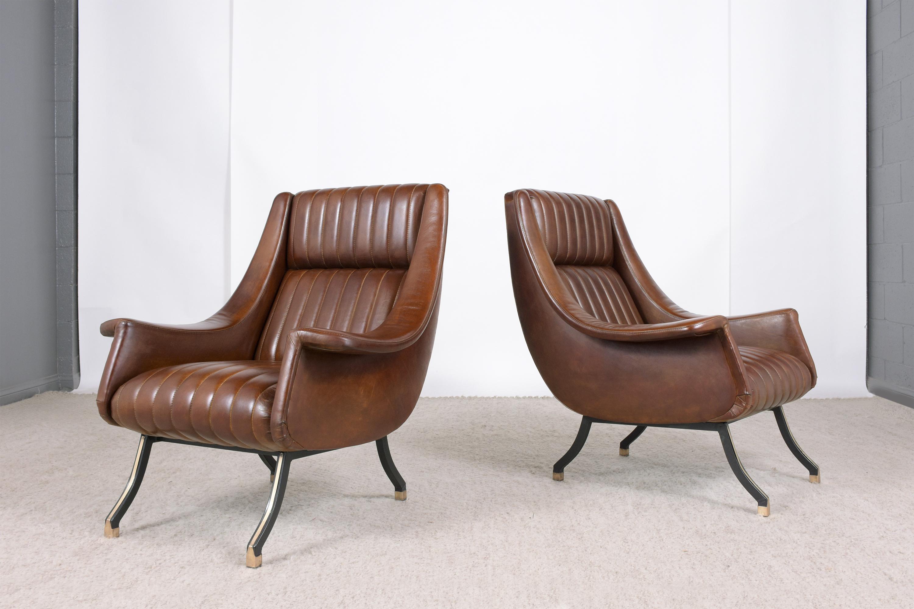 This vintage pair of Italian mid-century modern lounge chairs hand-crafted out of wood/iron combination was completed restored by our craftsmen team. The chairs are professionally upholstered in new English tan color leather with a tufted channel