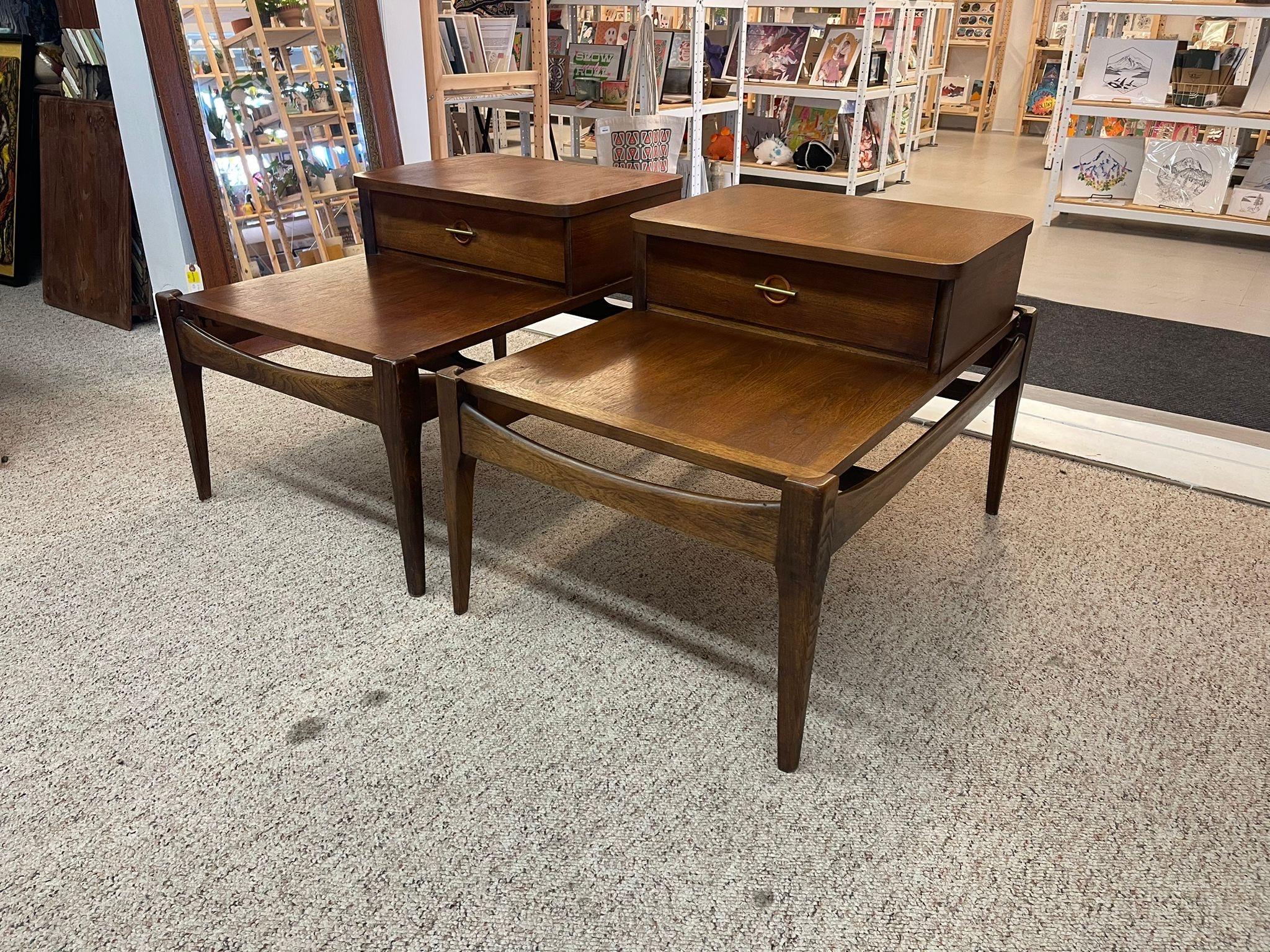These vintage pieces have beautiful walnut Toned wood. The single Dovetailed drawer has a recessed circular wood pull accented by a thin , horizontal brass strip. The sides and front have sculpted wood support stretchers. No Makers mark. Available
